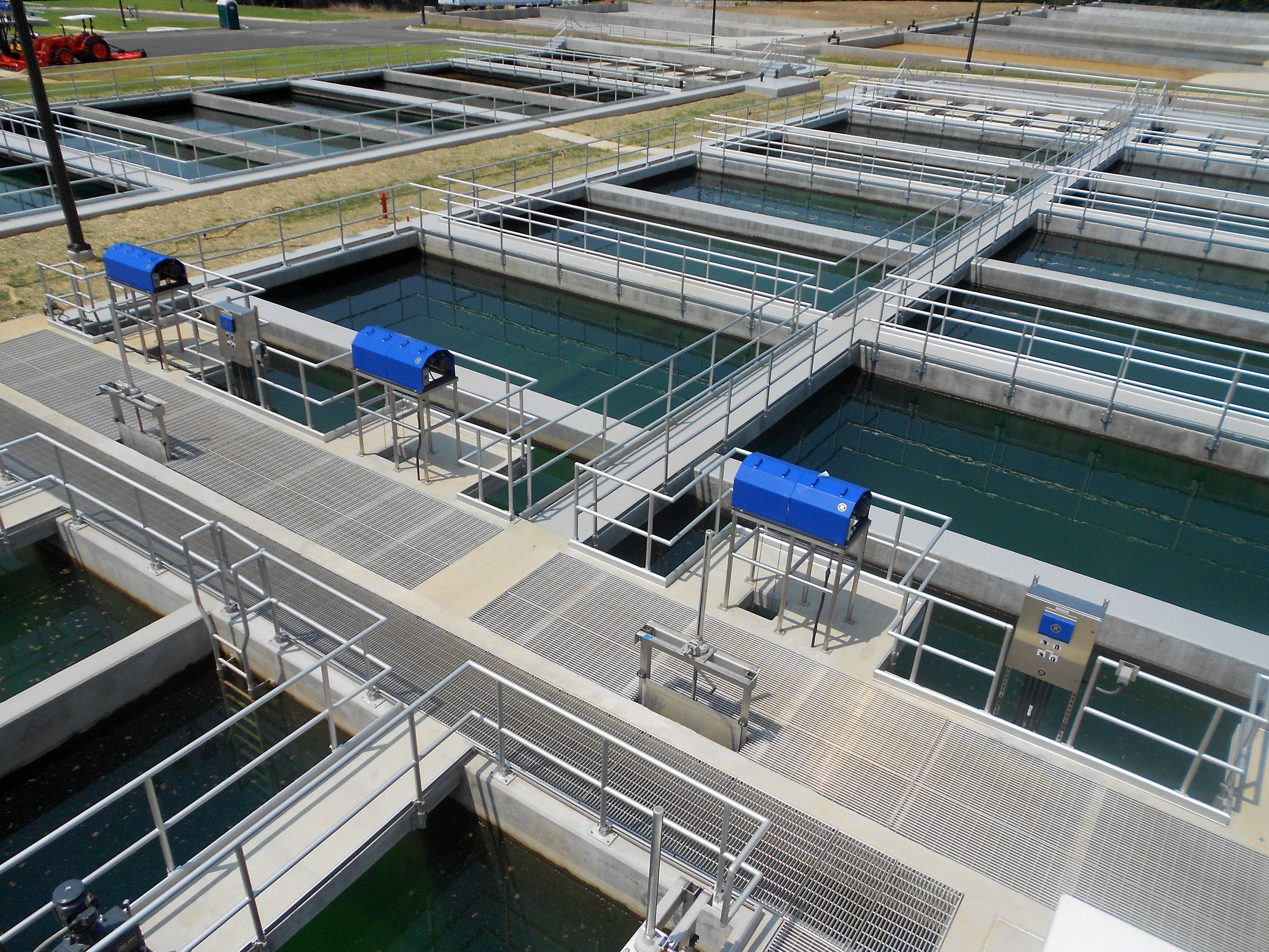 Multiple rectangular water treatment tanks with walkways and blue control boxes in an outdoor facility at Ft. Benning Water Treatment Plant - project by B Group Architecture, Inc.