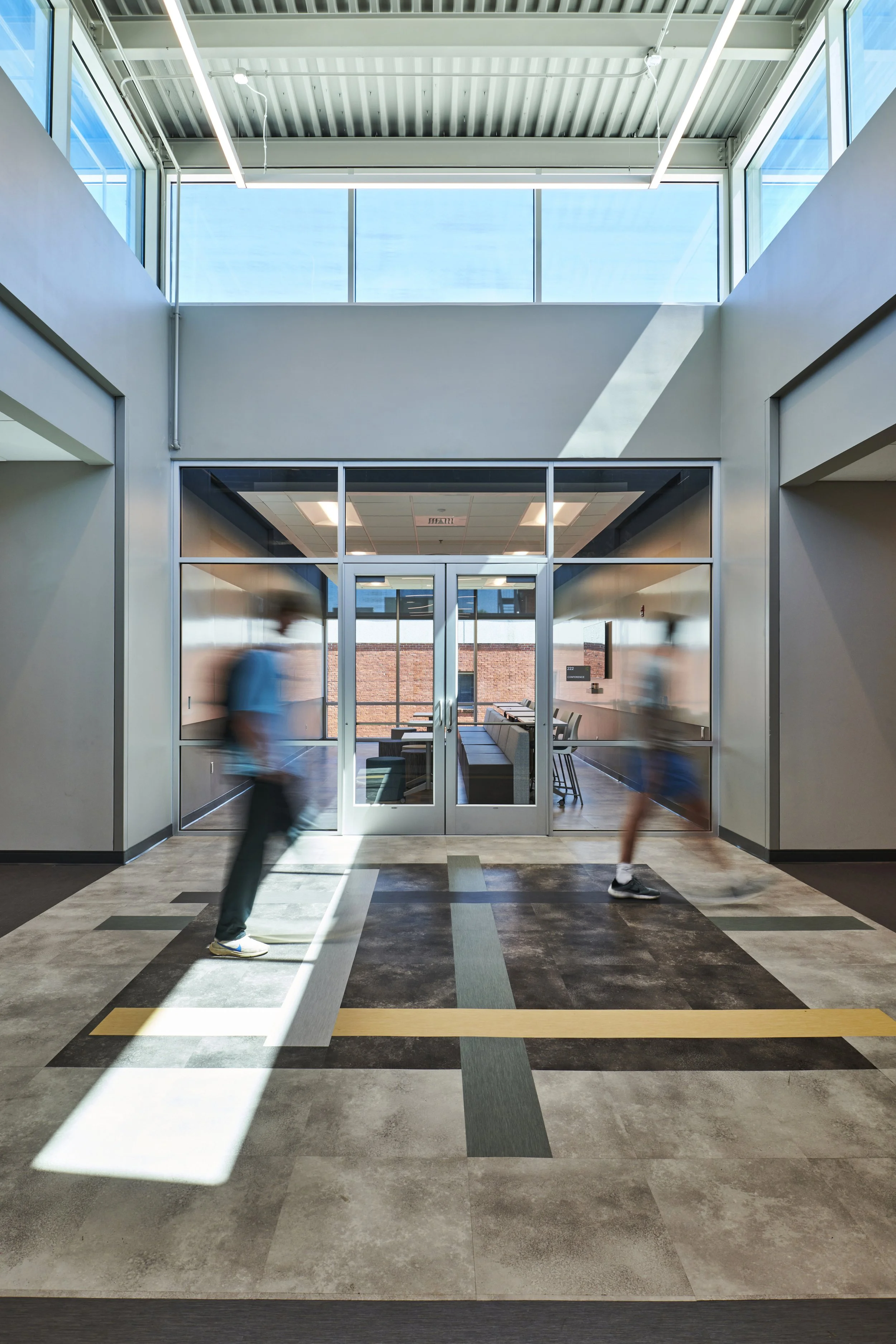 Modern high school corridor with high ceiling clerestory and interesting lvt tile pattern- project by B Group Architecture, Inc.