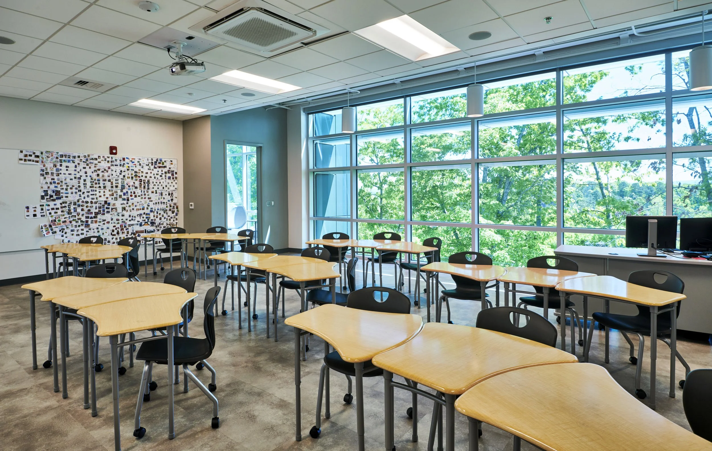 Collaborative classroom with curved tables, and chairs on casters. views to the exterior from large floor to ceiling glass windows -project by B Group Architecture, Inc.