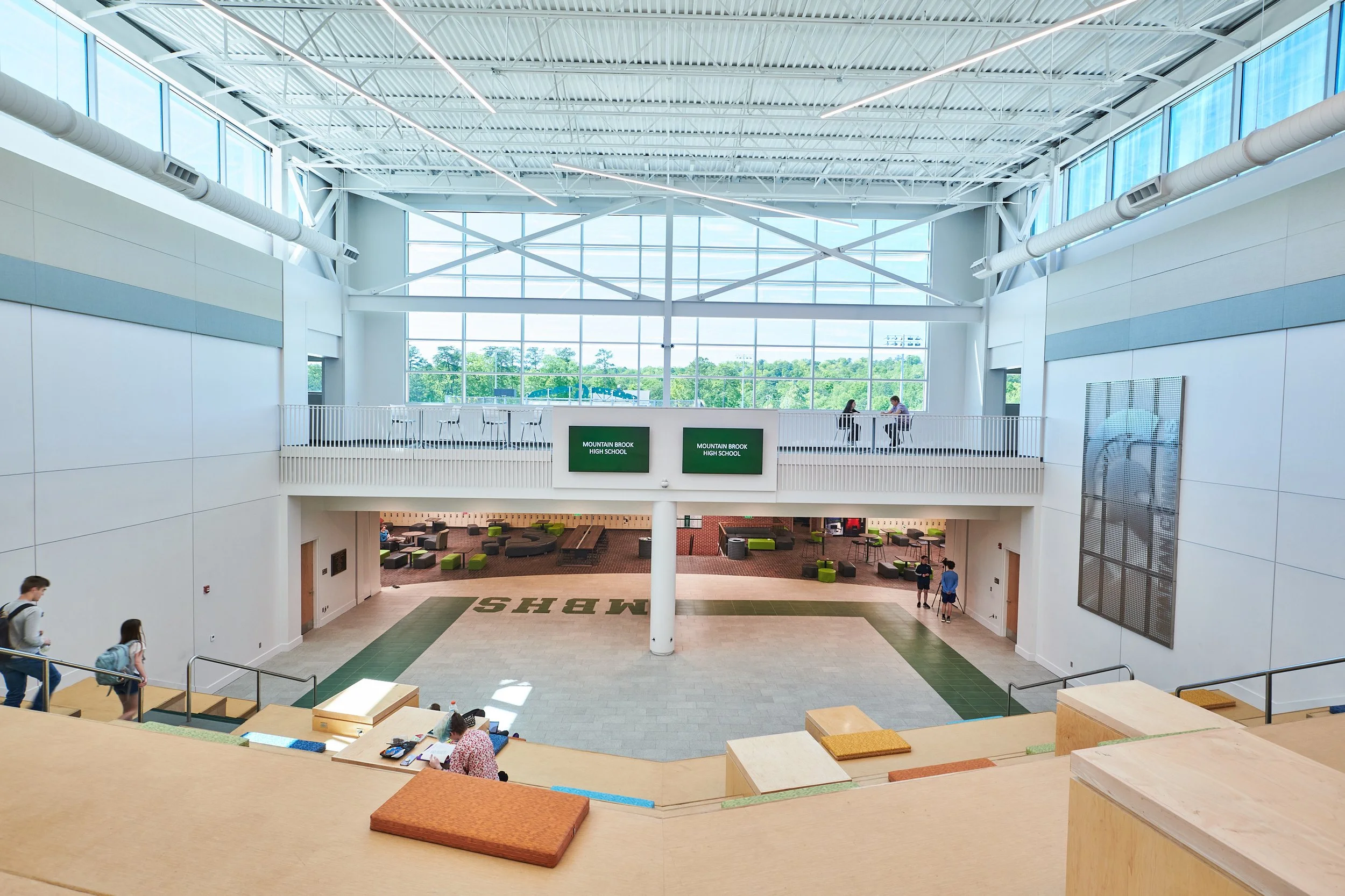 Interior view of a two story space with the tiered cushioned seating and stairs  showcasing large clerestory windows with terrific views and exposed structure- project by B Group Architecture, Inc.