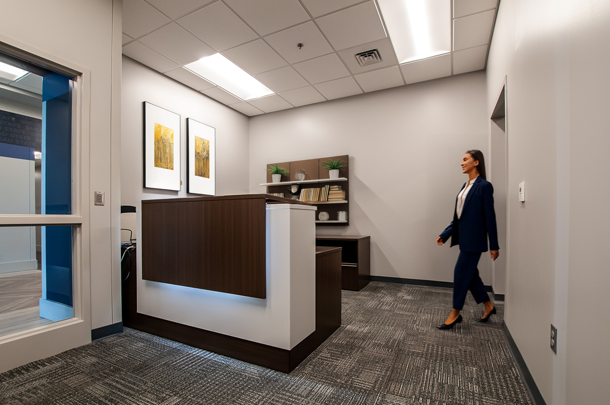 A office reception area with a white wall, a wooden backlit wood fountain edge counter.