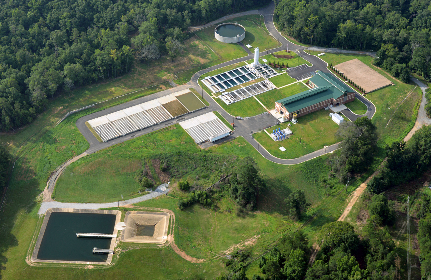 Aerial view of the Columbus Water Work wastewater treatment plant in Ft. Benning surrounded by trees, with tanks, pipelines, and processing buildings.  project by B Group Architecture Inc.