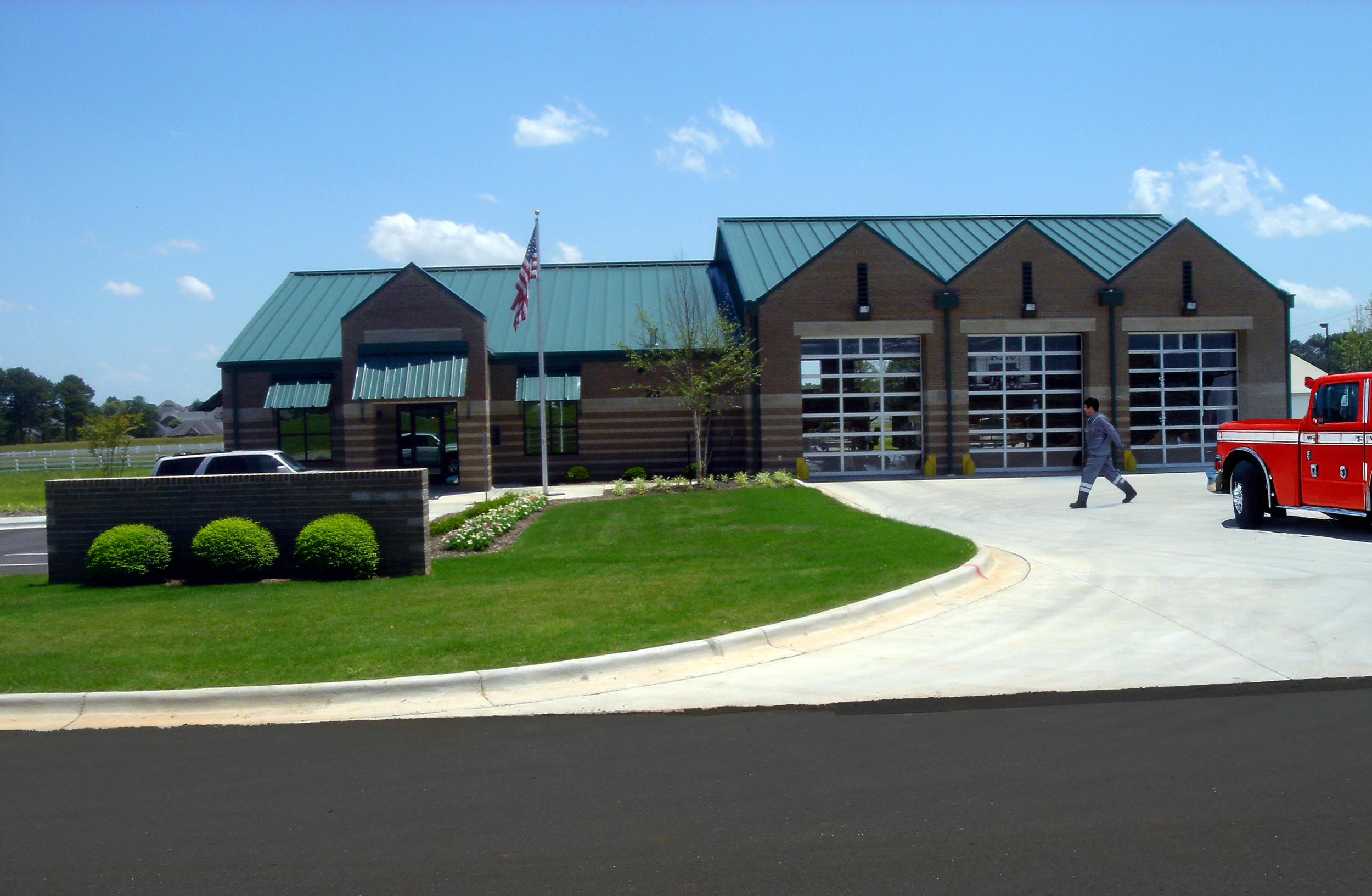 A modern fire station in Athens, AL with three large garage doors a metal roof and a gabled facade. project by B Group Architecture, Inc.
