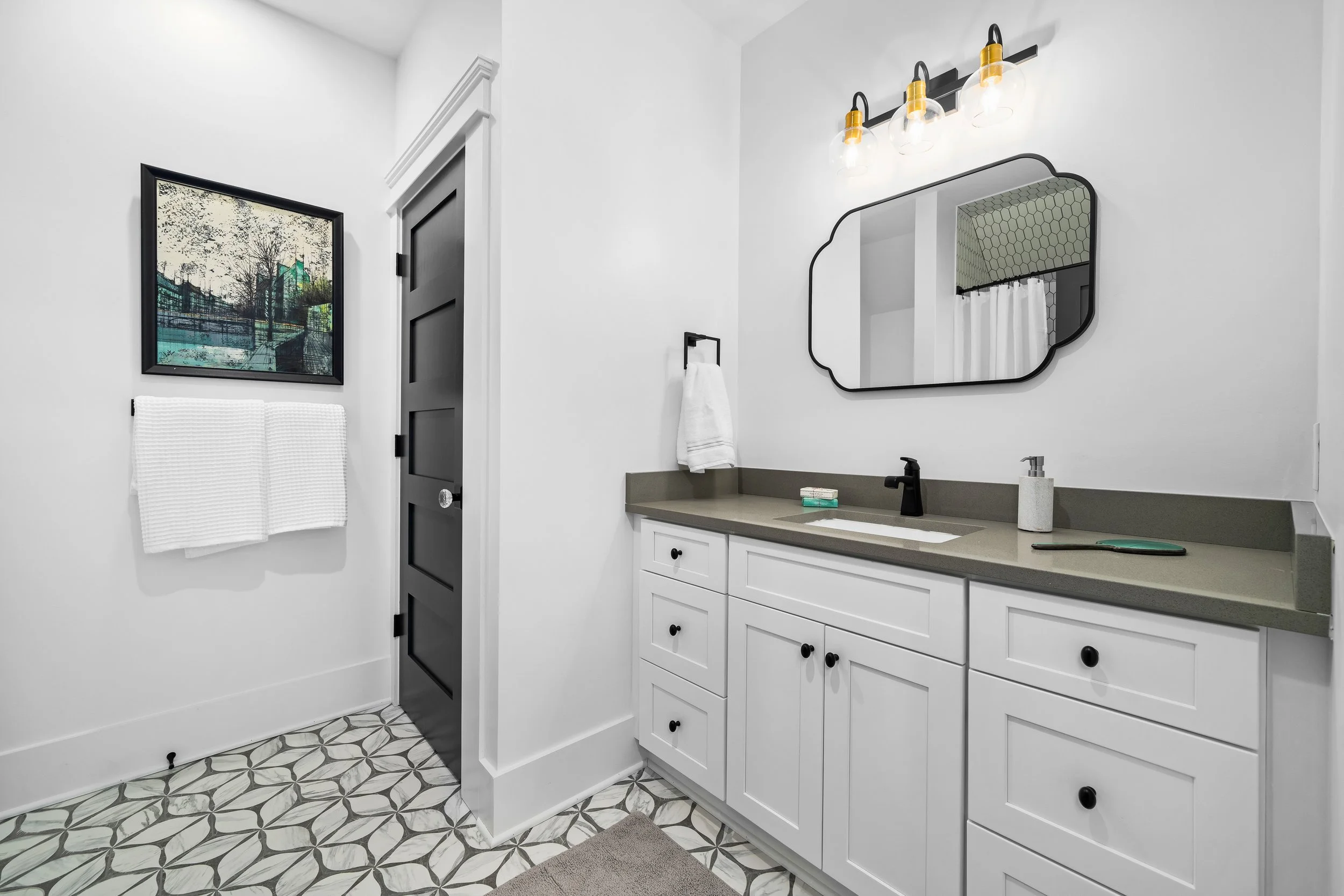 Bathroom with a white vanity with black fixtures and contemporary lighting. room has white walls and black doors. project by B Group Architecture, Inc.