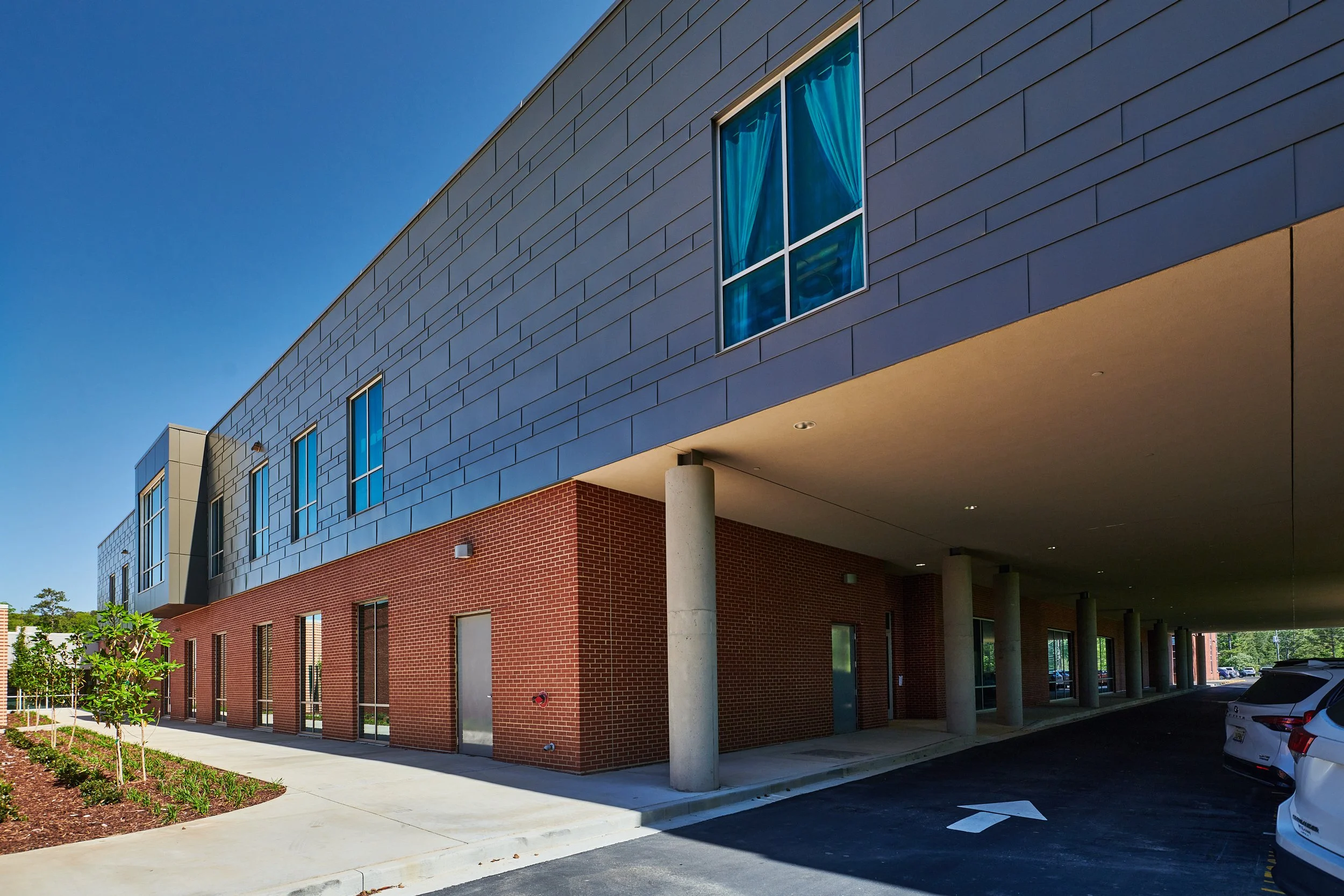 A view from below a high school where the second floor cantilevers over an existing drive to maximize the space - project by B Group Architecture, Inc.