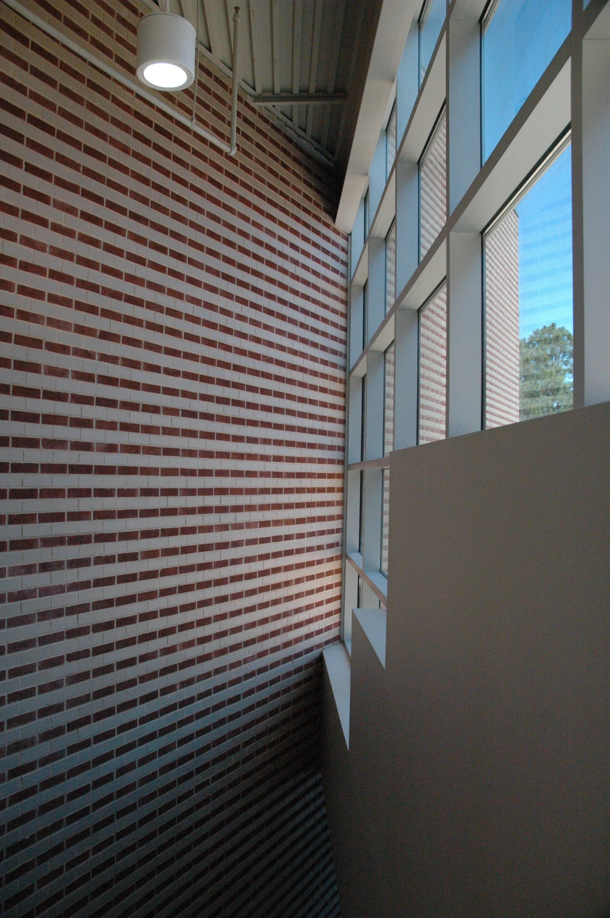 A modern interior space featuring a brick patterned wall, large windows with anodized frames. project by B Group Architecture, Inc.