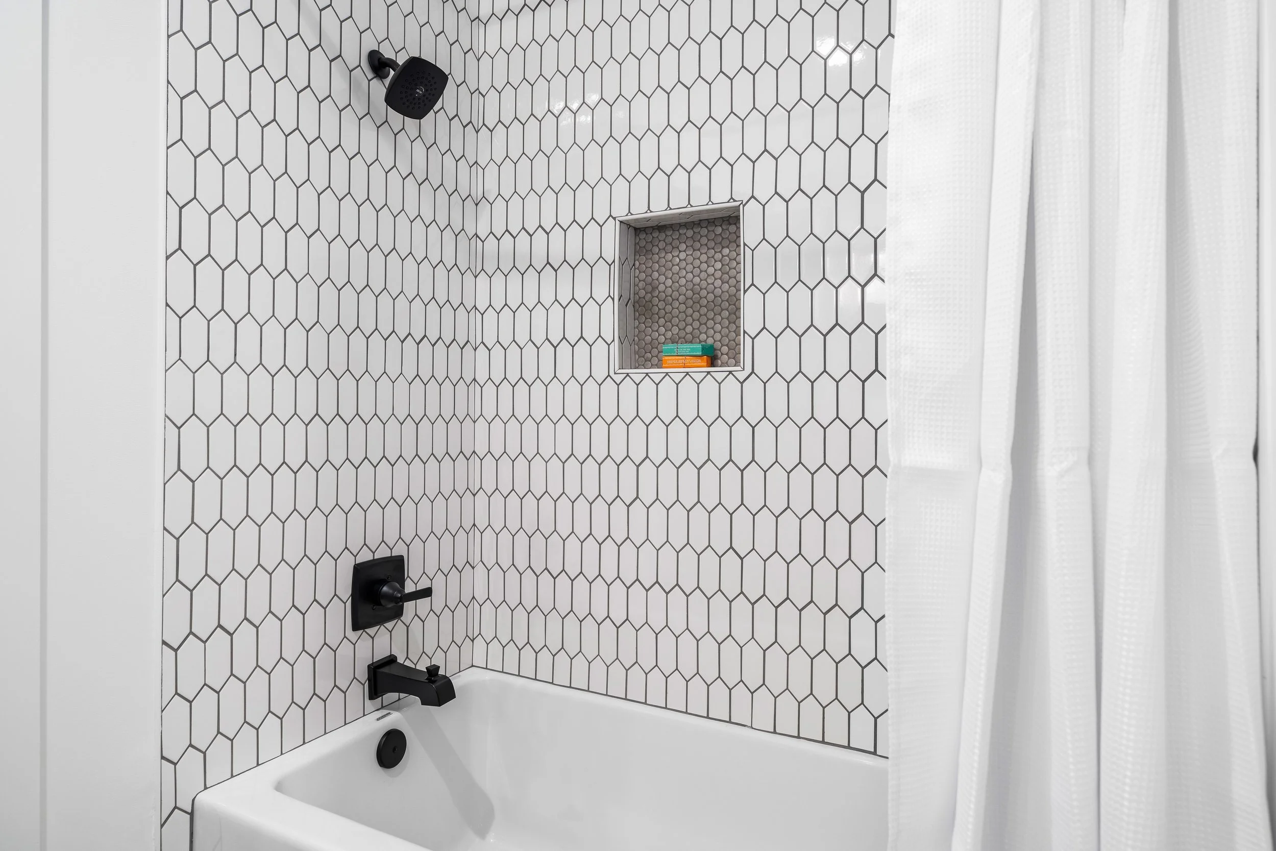 Bathroom view of a tub with tradition white marble tile and black fixtures. project by B Group Architecture, Inc.