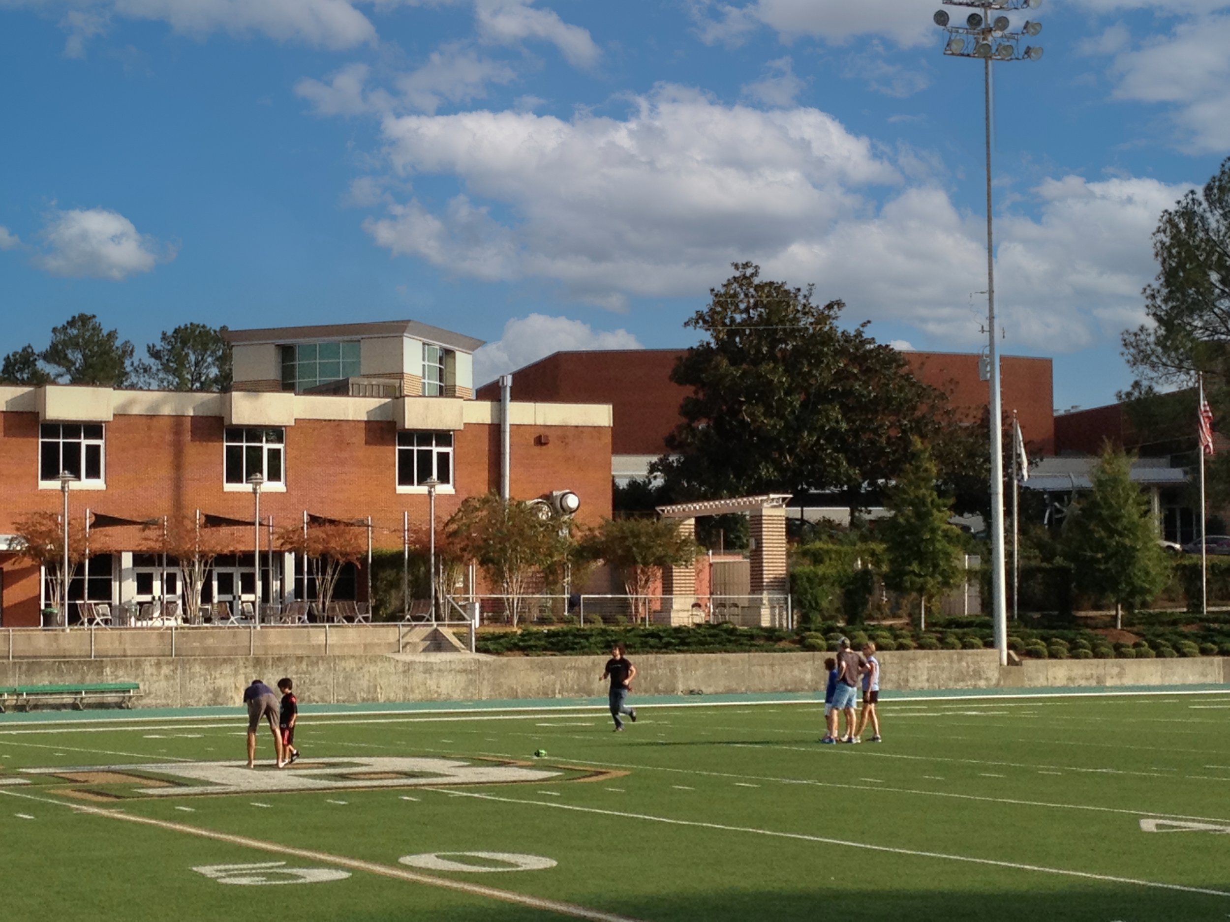 View of Mountain Brook High School football field with a running track, and the school in the background. project by B Group Architecture, Inc.