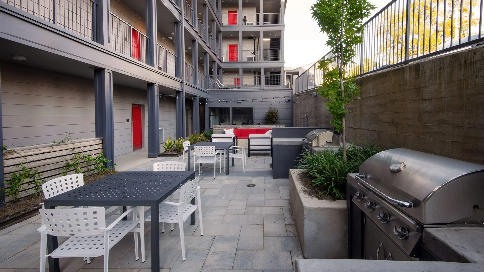 Outdoor Entertainment area with Outdoor Grilling and BBQ Area. Beyond you see red doors leading into the condo units- project by B Group Architecture, Inc.