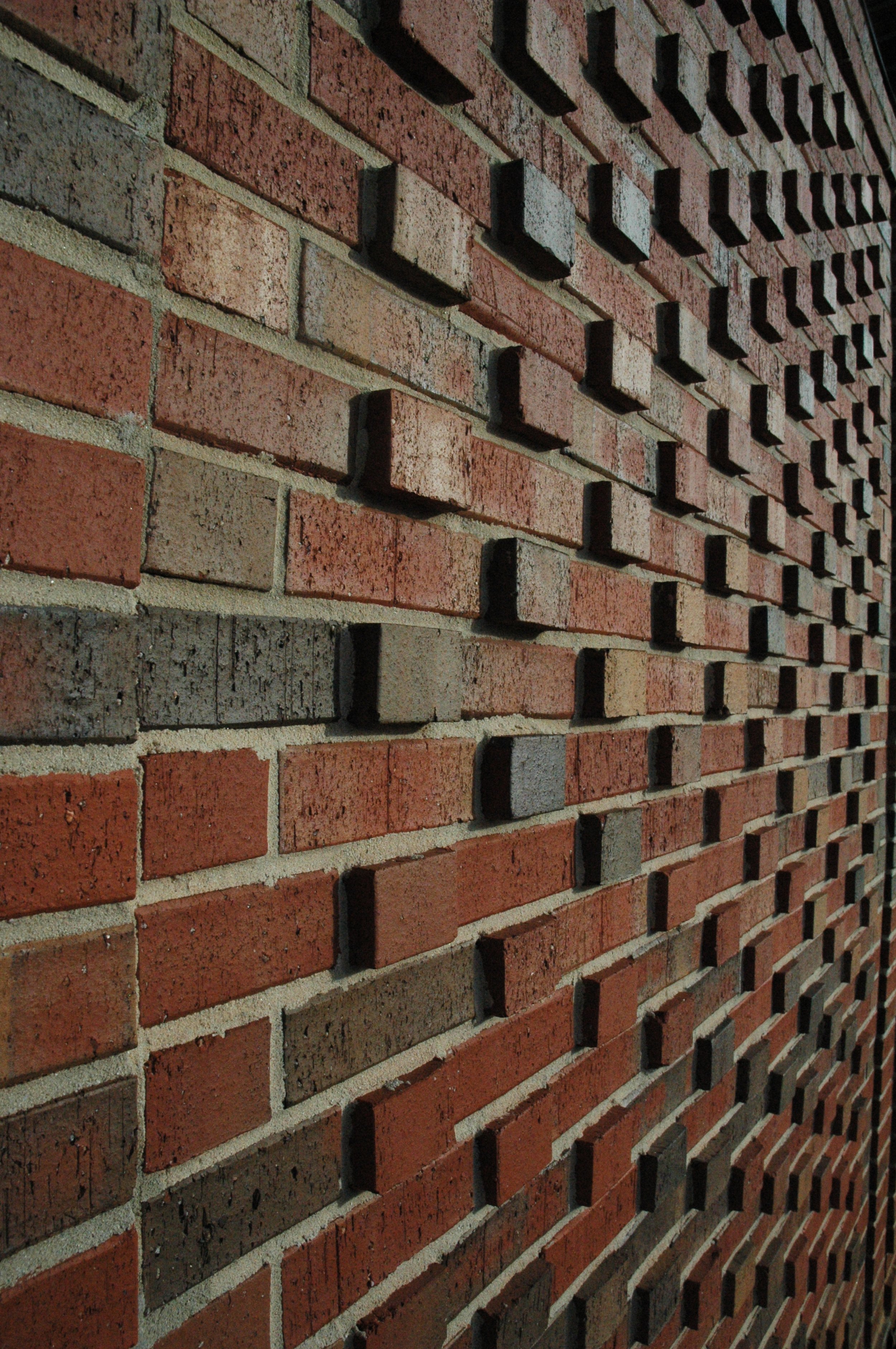 Close-up view of a brick wall with protruding bricks creating a textured pattern.- project by B Group Architecture, Inc.