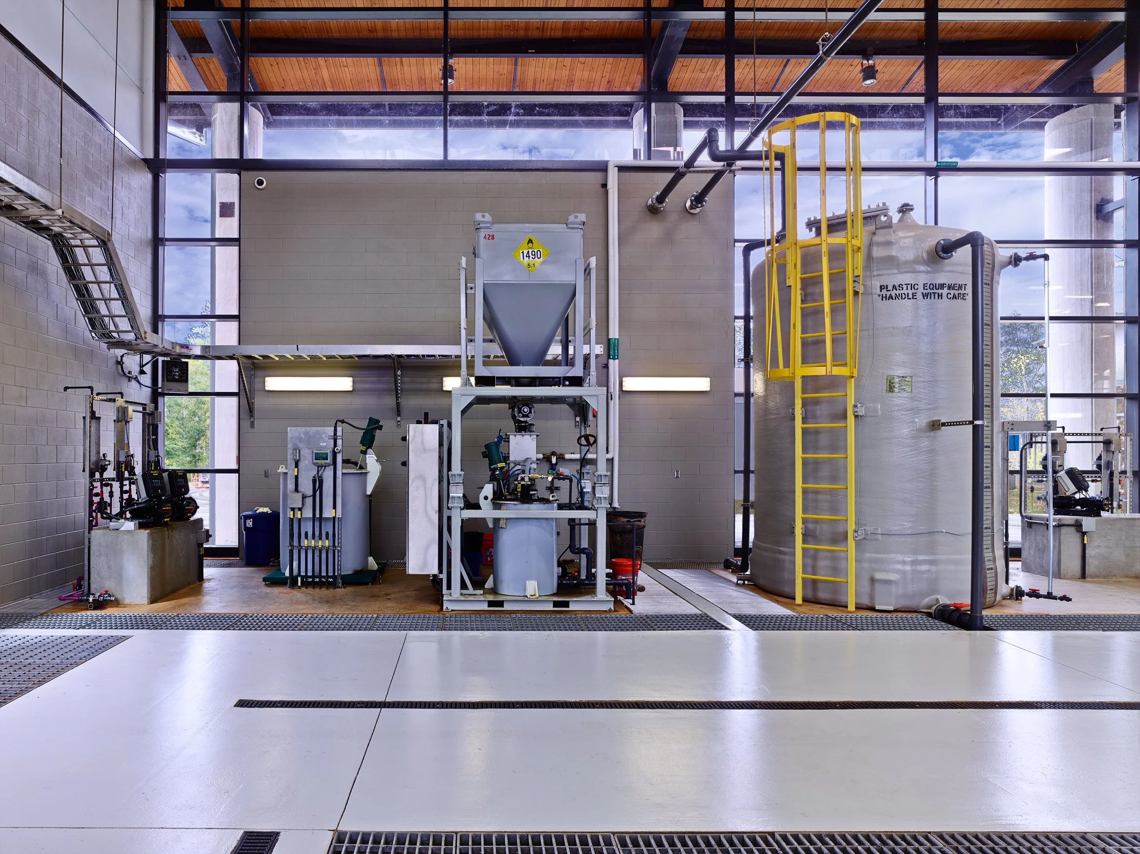 Industrial water treatment facility with tanks, and filtration equipment with a backdrop of glass walls. project by B Group Architecture,  Inc.