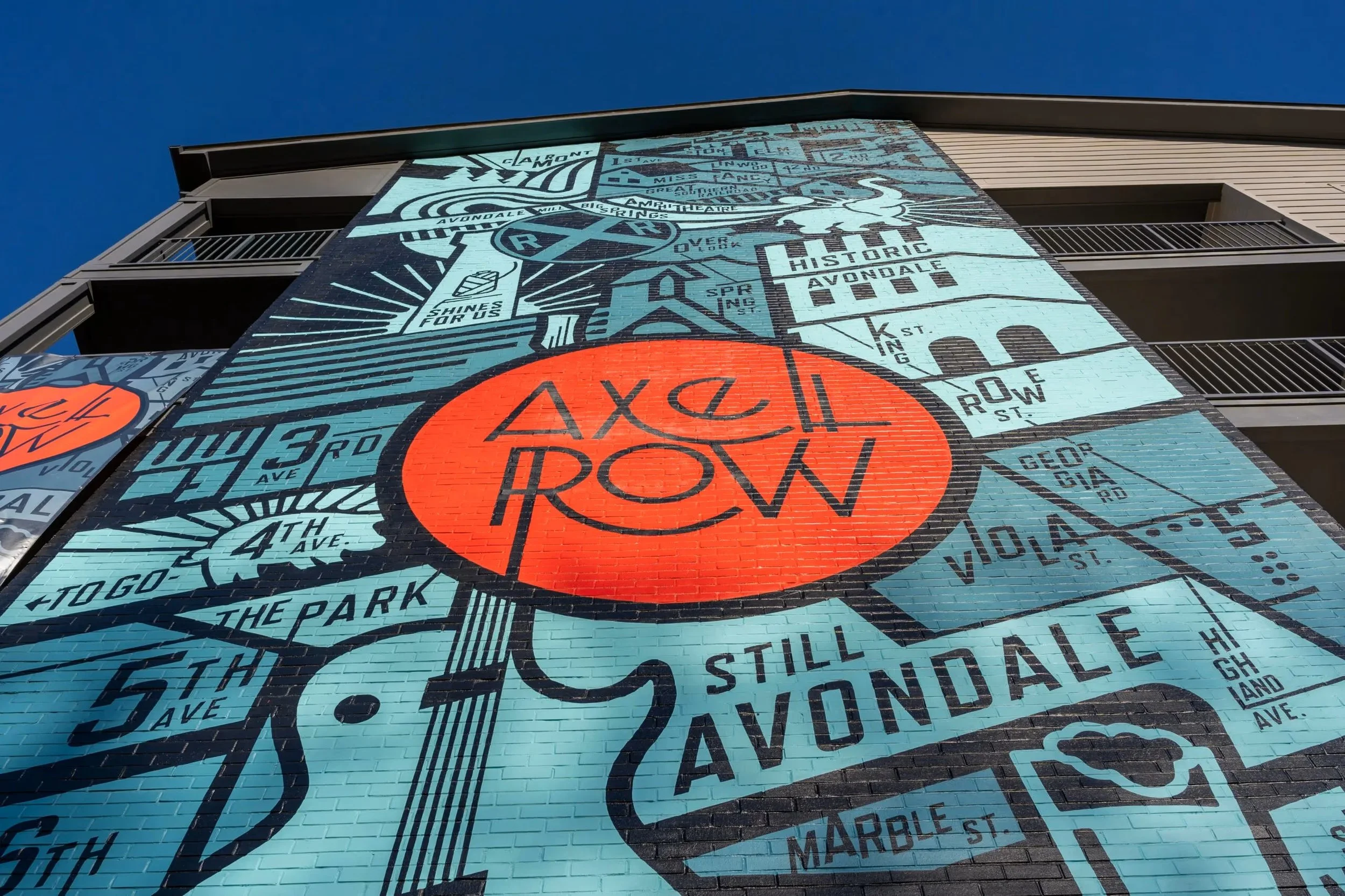 Colorful mural on a building wall depicting a stylized map of Avondale with street names and landmarks, featuring a large red circle with the words 'Axel Row' in the center against a blue background. project by B Group Architecture, Inc.