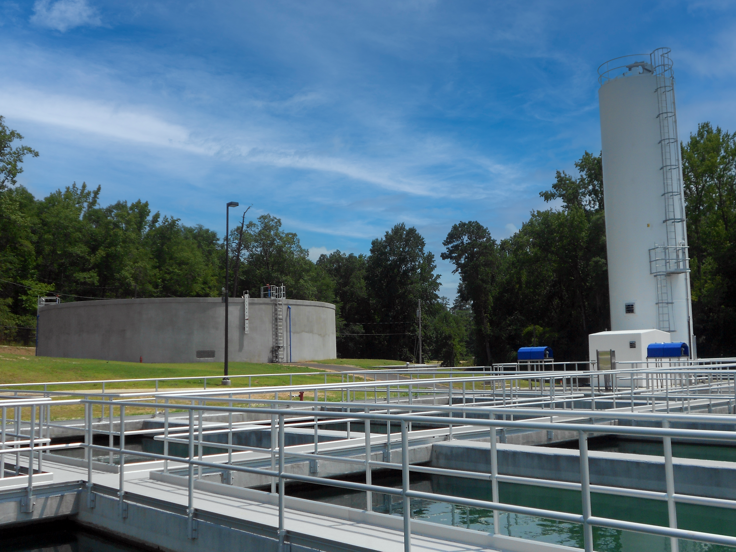Multiple water treatment tanks with walkways and blue control boxes in an outdoor facility at Ft. Benning Water Treatment Plant - project by B Group Architecture, Inc.