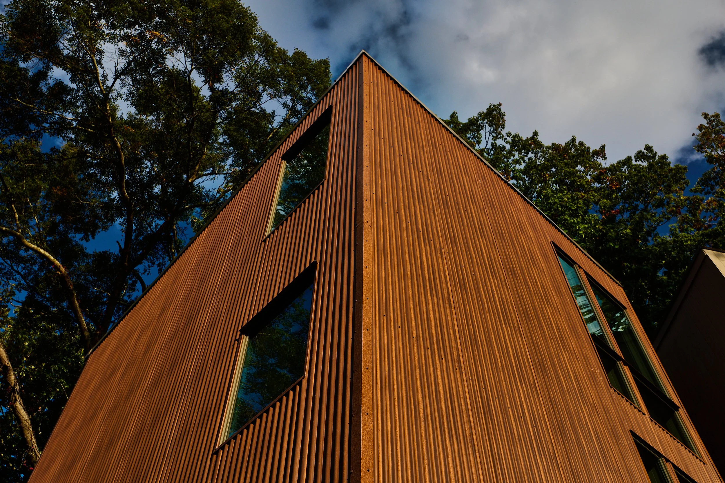 A corner view of the new stair tower in a corten metal with punched openings. project by B Group Architecture, Inc.