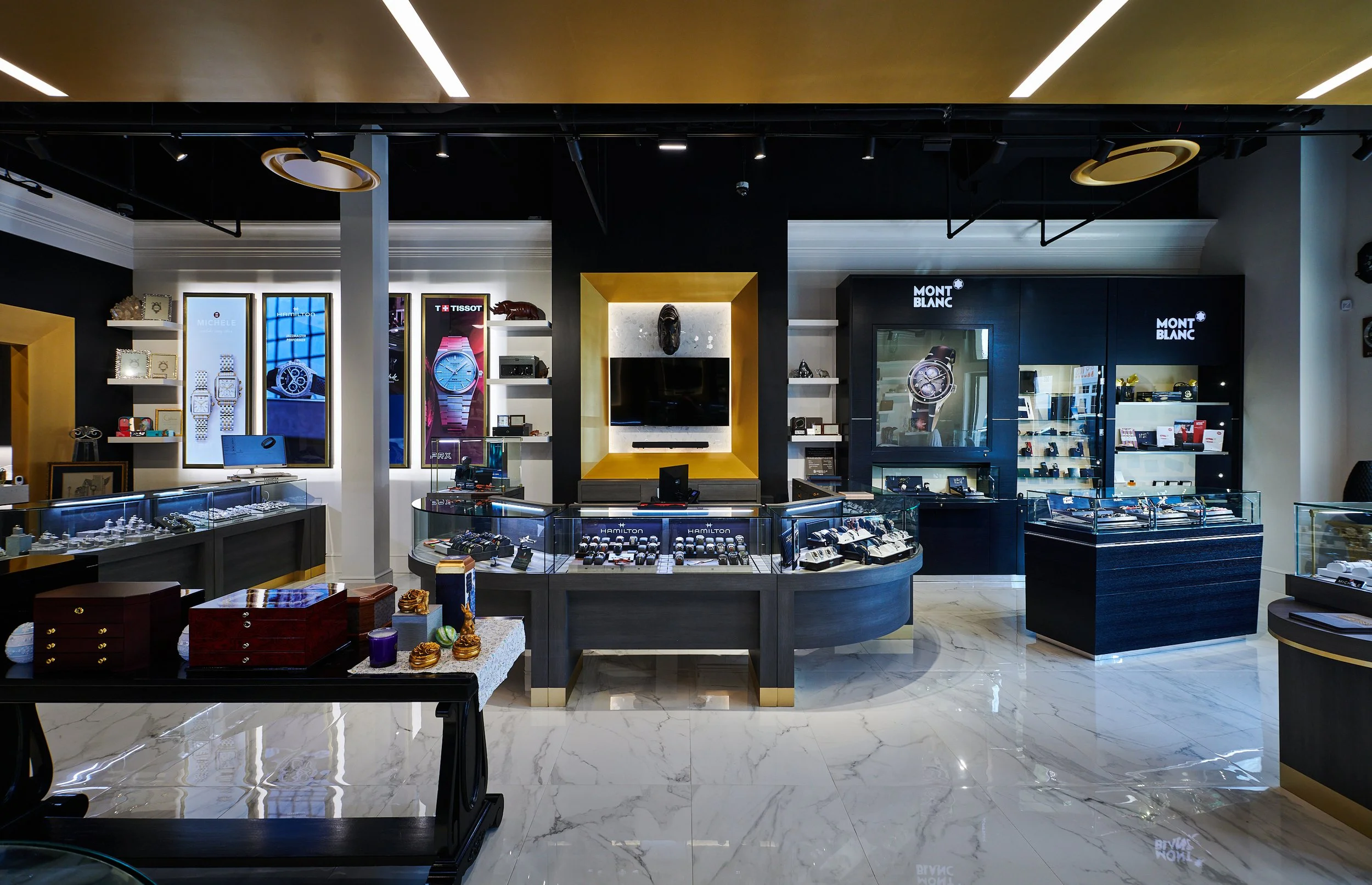 Interior of Barton Clay Fine Jewelers with display cases, shelves of jewelry, and a gold ceiling cloud and a Mont Blanc counter. project by B Group Architecture, Inc 