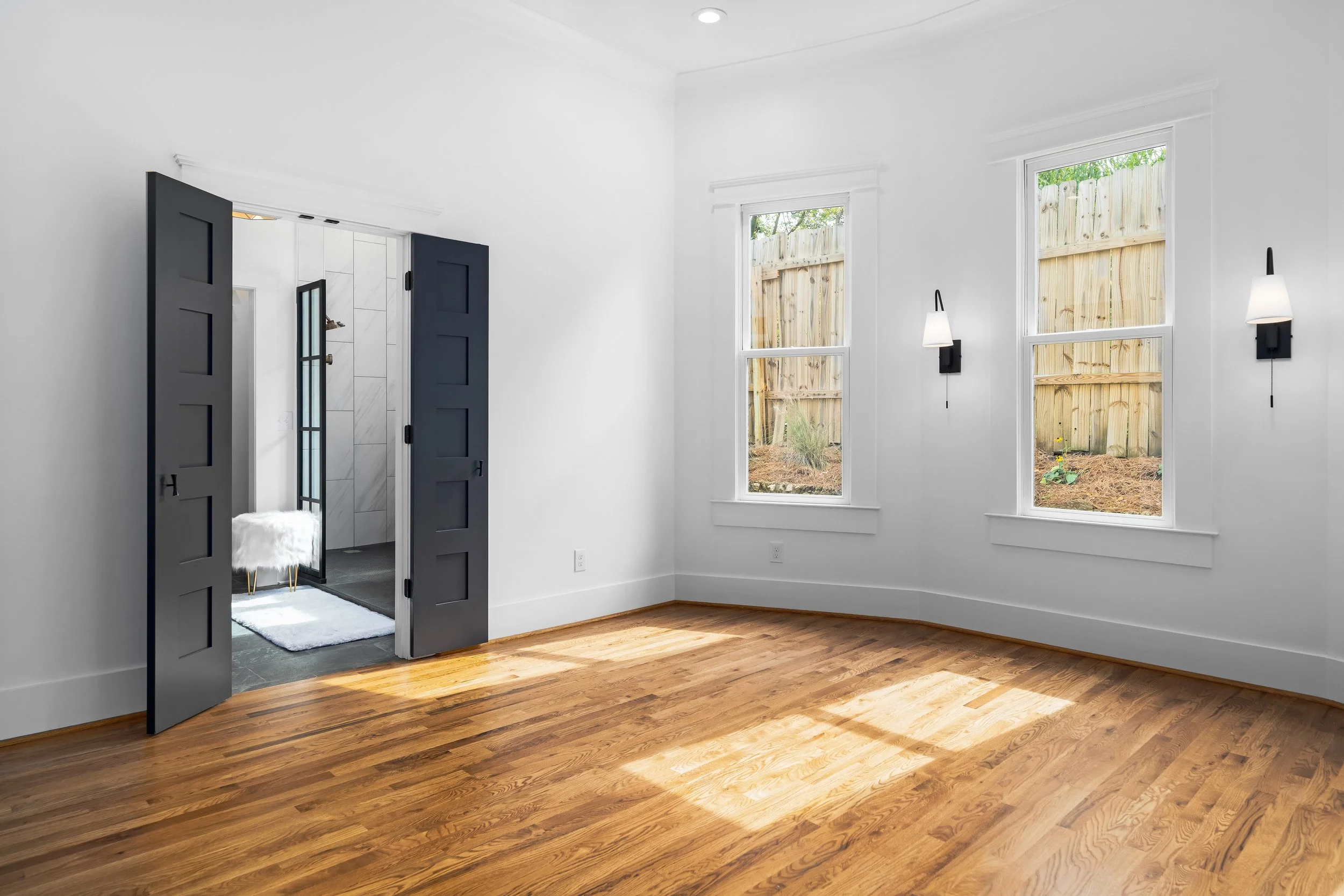 Bedroom with a white wall, large windows allowing natural light to shine in. project by B Group Architecture, Inc.