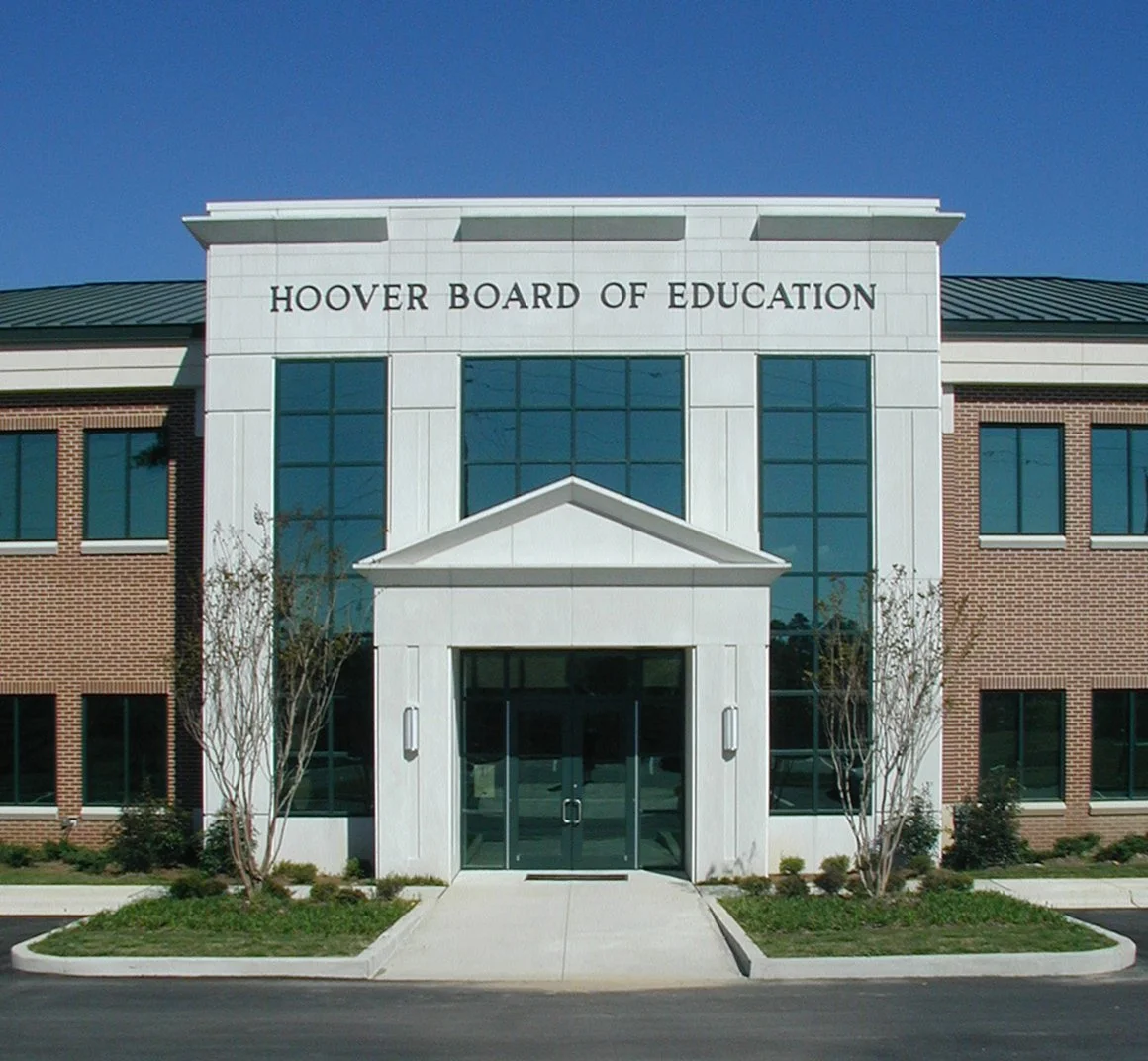 A modern Board of Education with stone entry facade, large glass windows, and brick and cast stone. project by B Group Architecture, Inc.