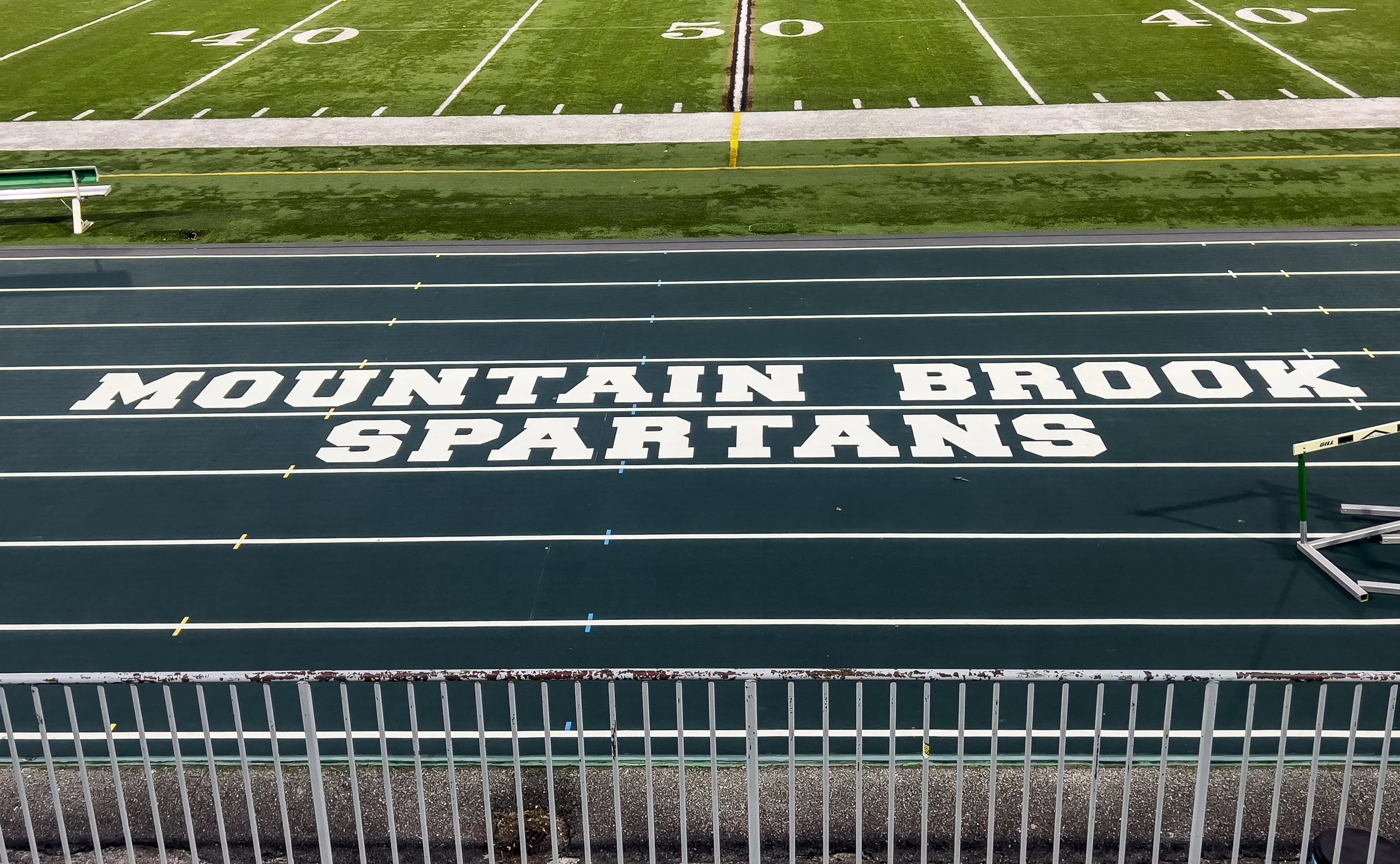 A running track with the words 'Mountain Brook Spartans' painted across multiple lanes.