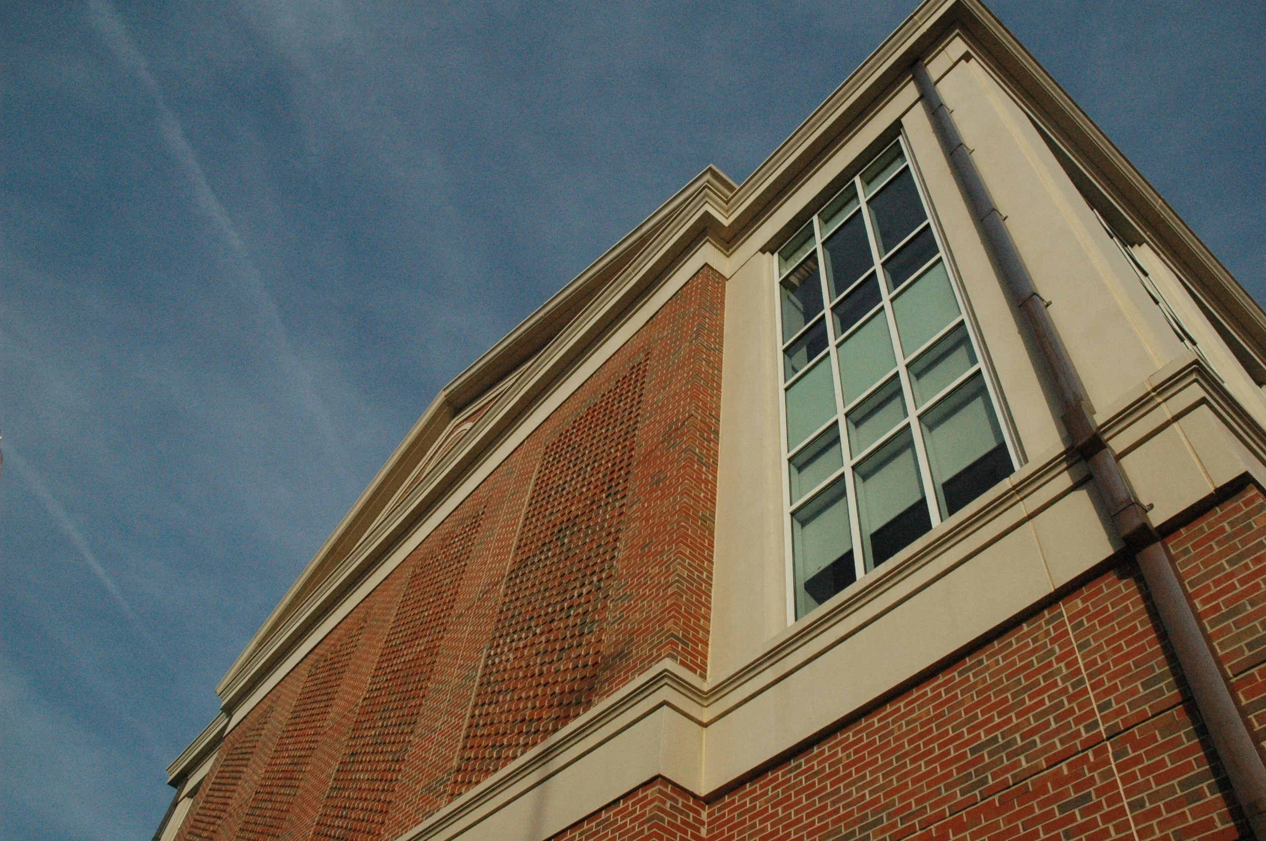 Looking up at the corner of a brick and cast stone building with large windows against a blue sky  - project by B Group Architecture, Inc.