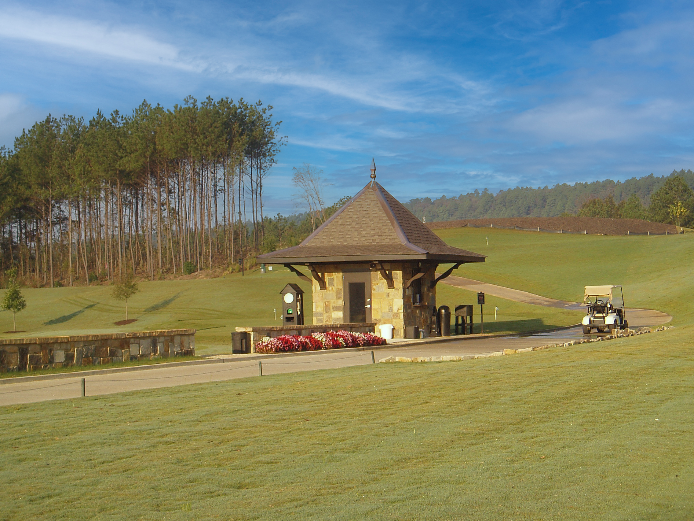 Ballantrae Golf Club stone guard house stands on a grassy hill. The sky is clear and blue.  project by B Group Architecture Inc. 