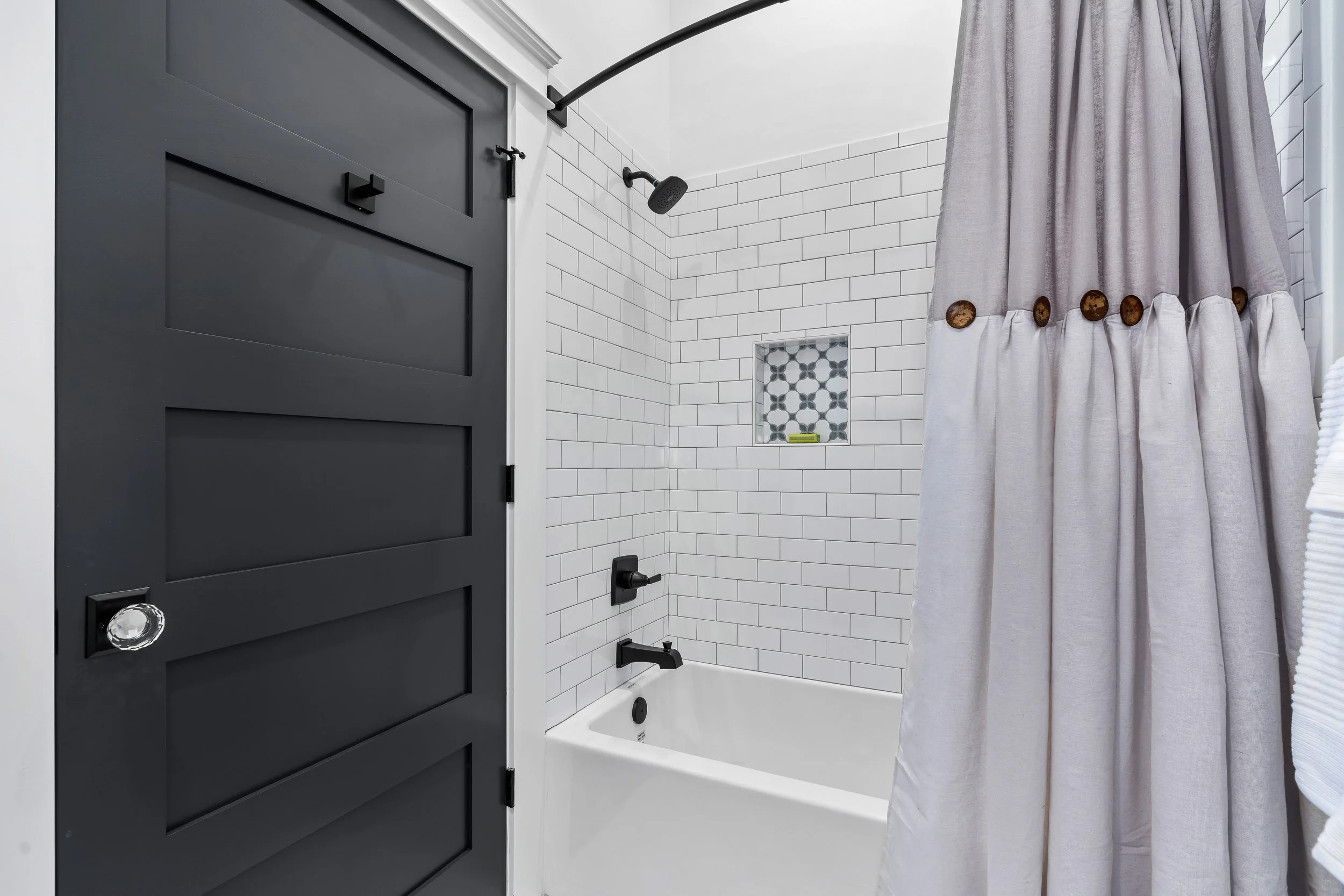 Bathroom view of a tub with tradition white marble tile and black fixtures. project by B Group Architecture, Inc.