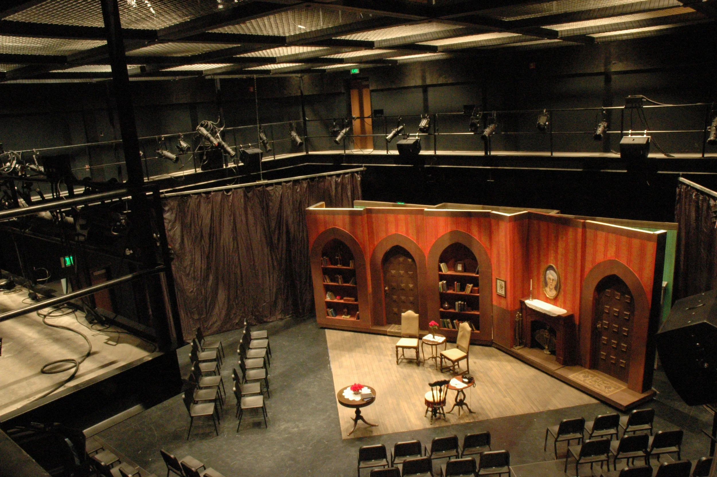 Black box theater stage set arranged for an audience and stage lights and grid overhead. - project by B Group Architecture, Inc.