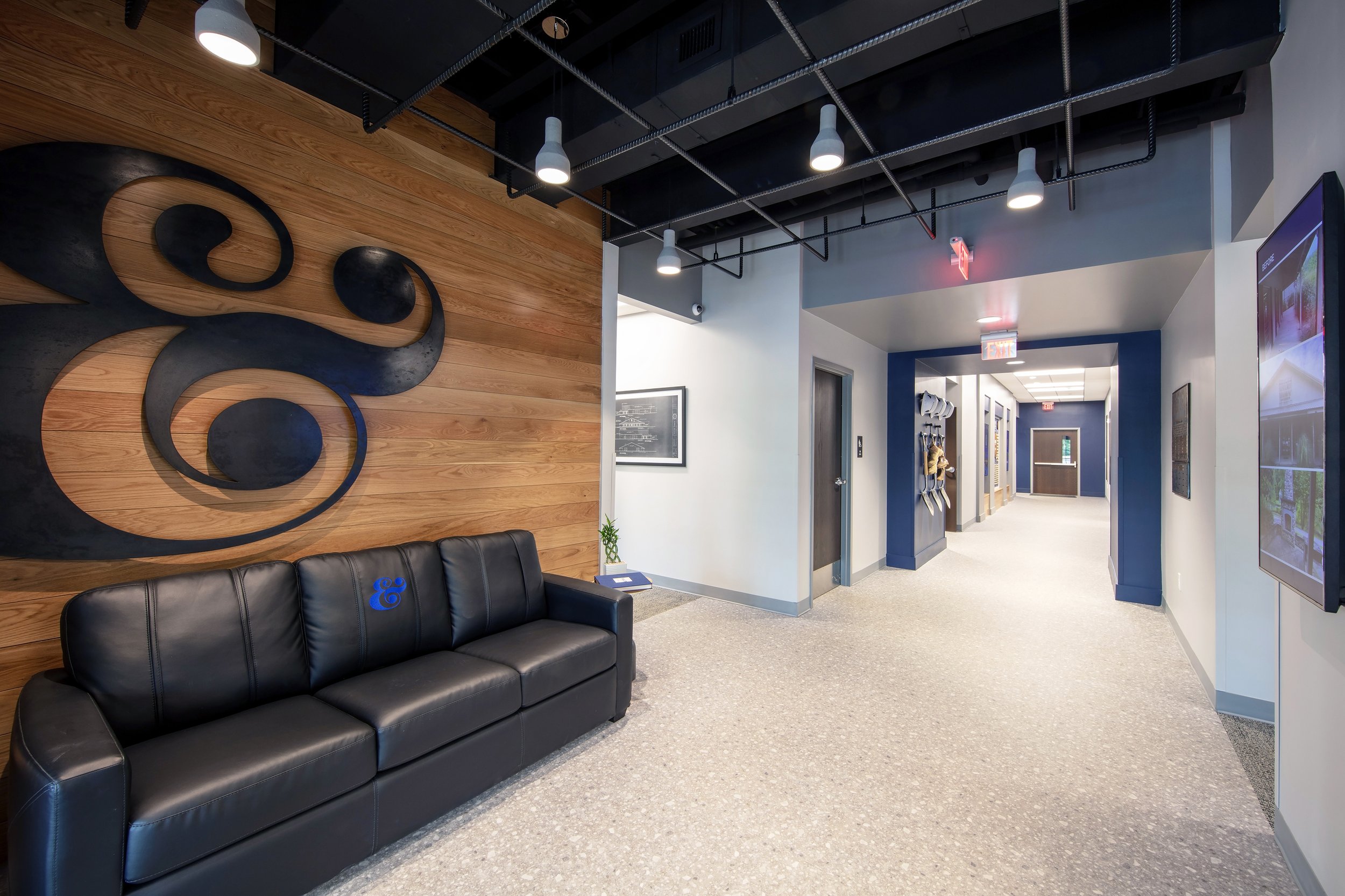 Modern training facility lobby for Brasfield & Gorrie with a wood accent wall with a steel ampersand logo. project by B Group Architecture, Inc.