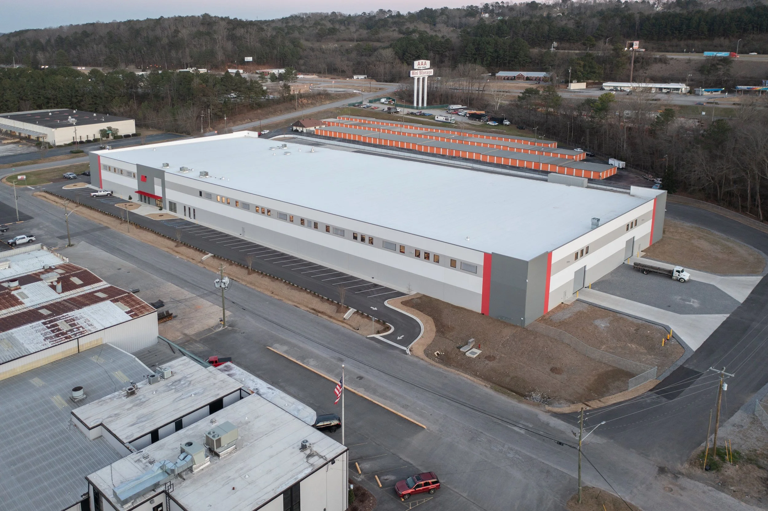 An exterior view of a modern building for Motion Industries Fluid Power Shop with their Mi logo on the wall, large glass doors at the entrance and tilt-up concrete construction. project by B Group Architecture, Inc.