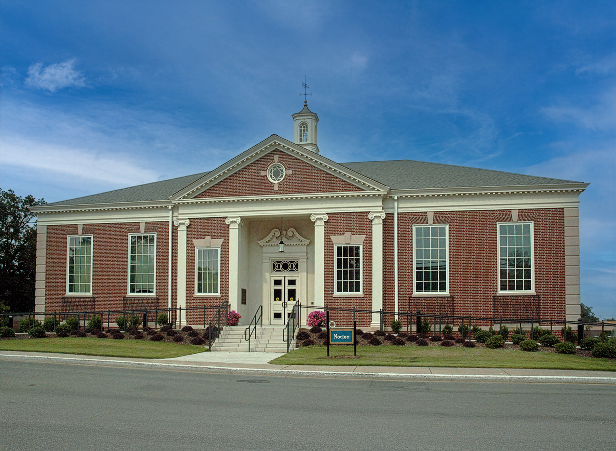 Norton library renovation has traditional red brick and cast stone trim, large windows, and a small white steeple on the roof, set on a Snead State college campus. - project by B Group Architecture, Inc.