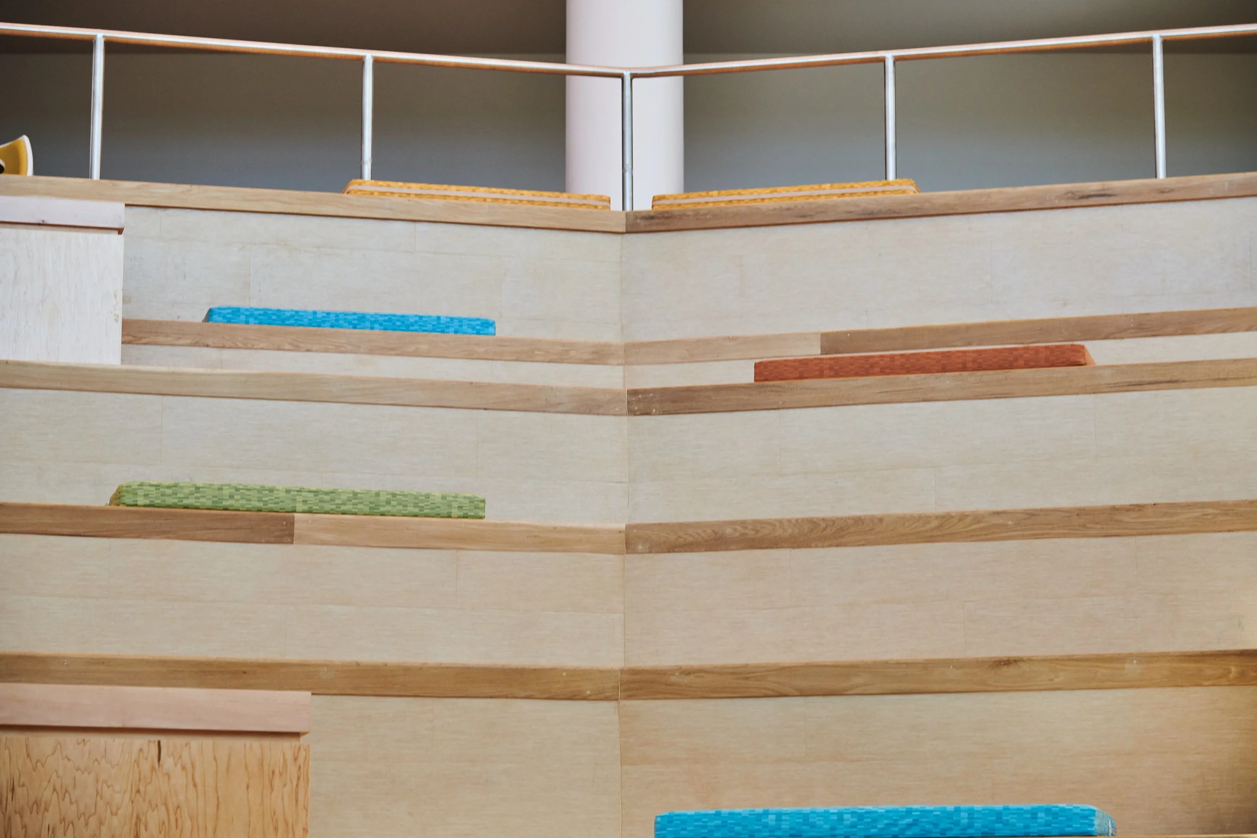 Colorful cushions on tiered high school commons seating- project by B Group Architecture, Inc.