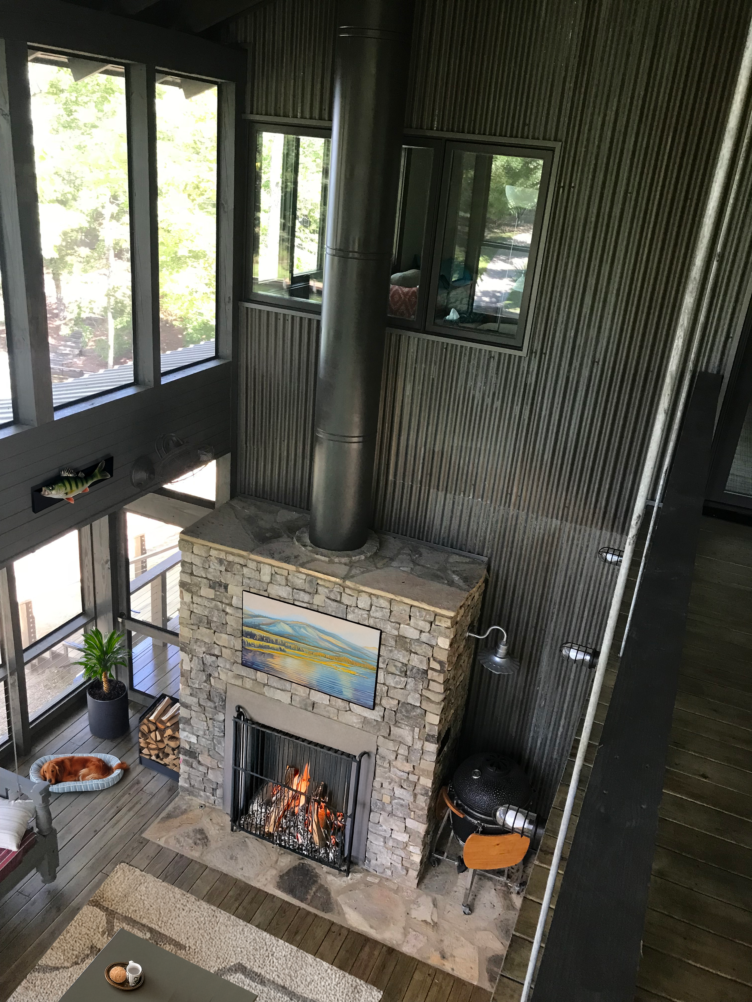 A living room view at a lake house in Pelham, AL looking down at the stone fireplace a a light filled space. project by B Group Architecture, Inc.