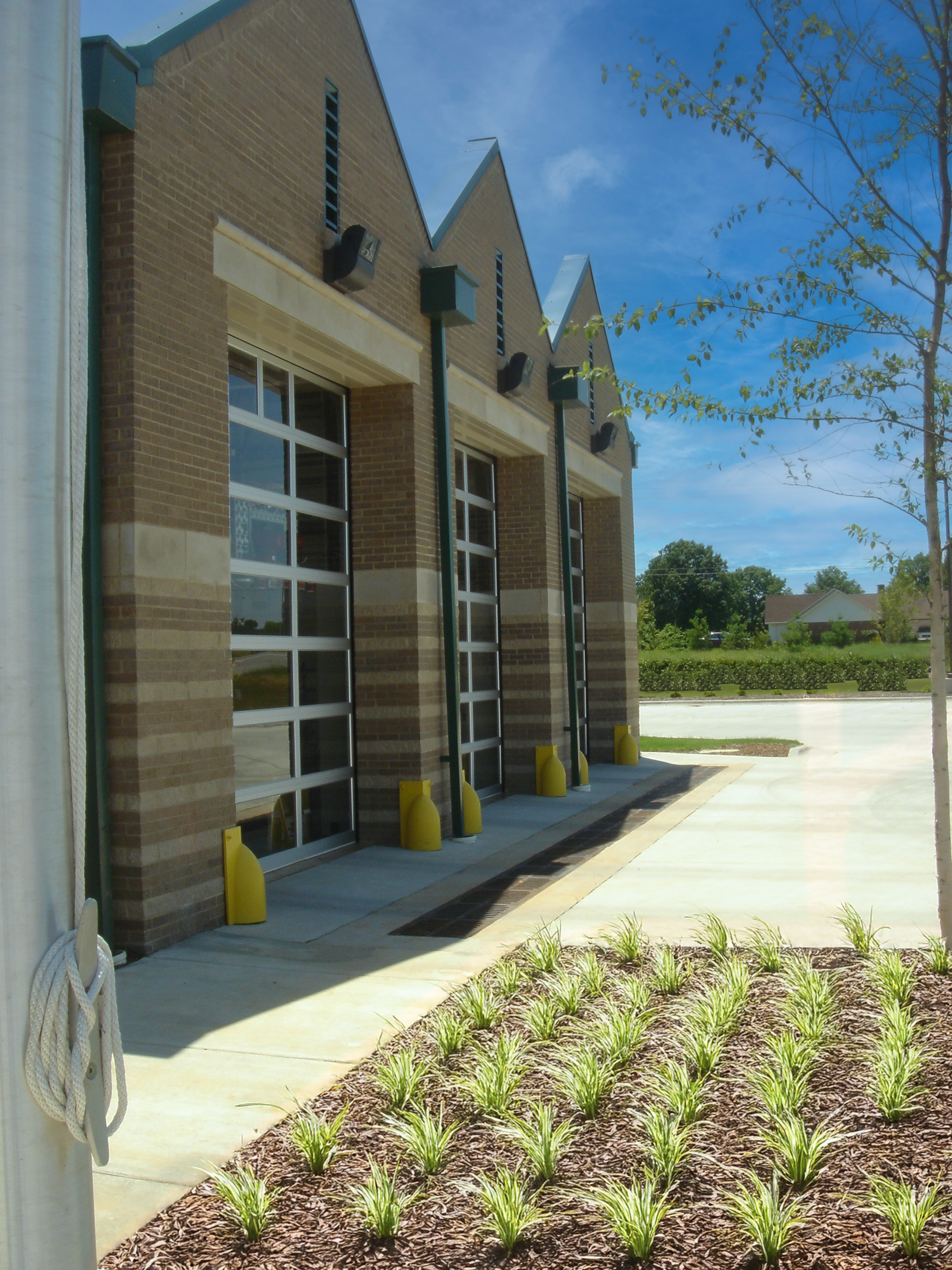 A modern fire station in Athens, AL with three large garage doors a metal roof and a gabled facade. project by B Group Architecture, Inc.