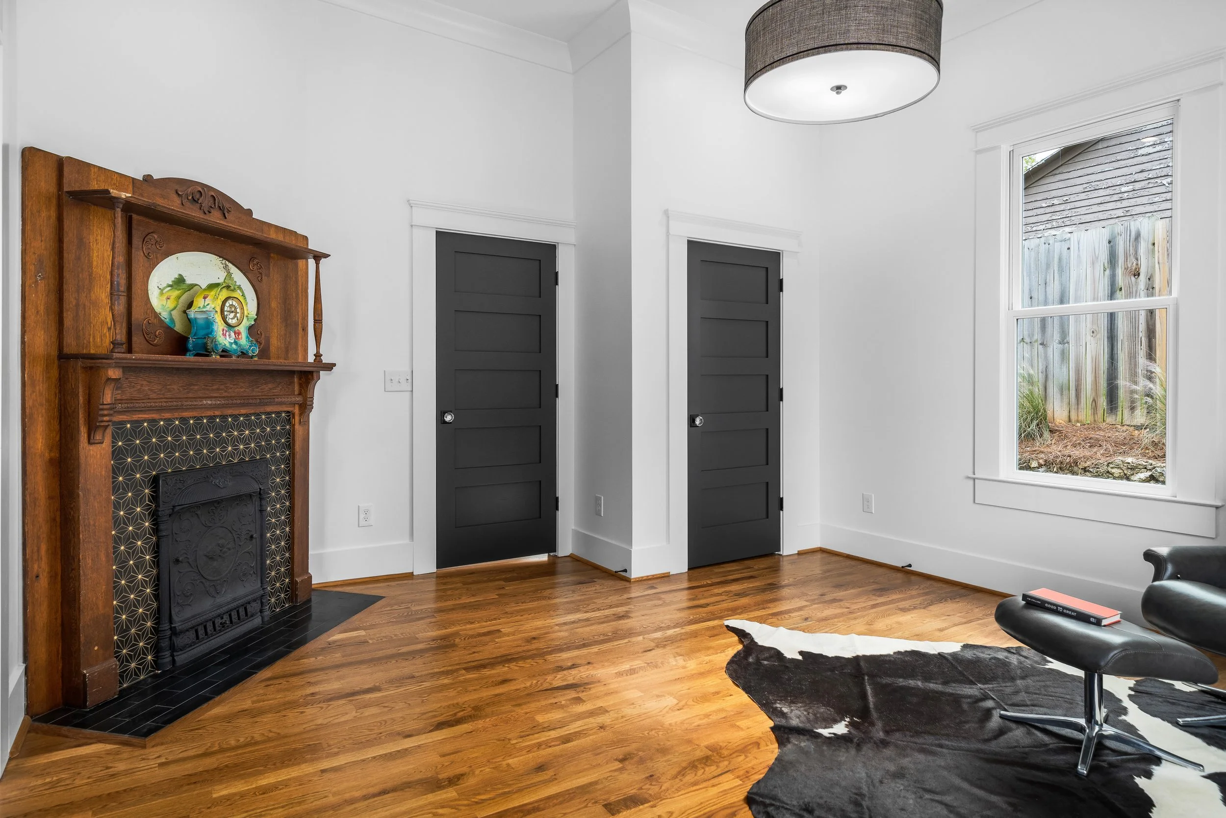 Bedroom study with hardwood floors, historic original wood and tile fireplace, dark gray doors with white walls. project by B Group Architecture, Inc.