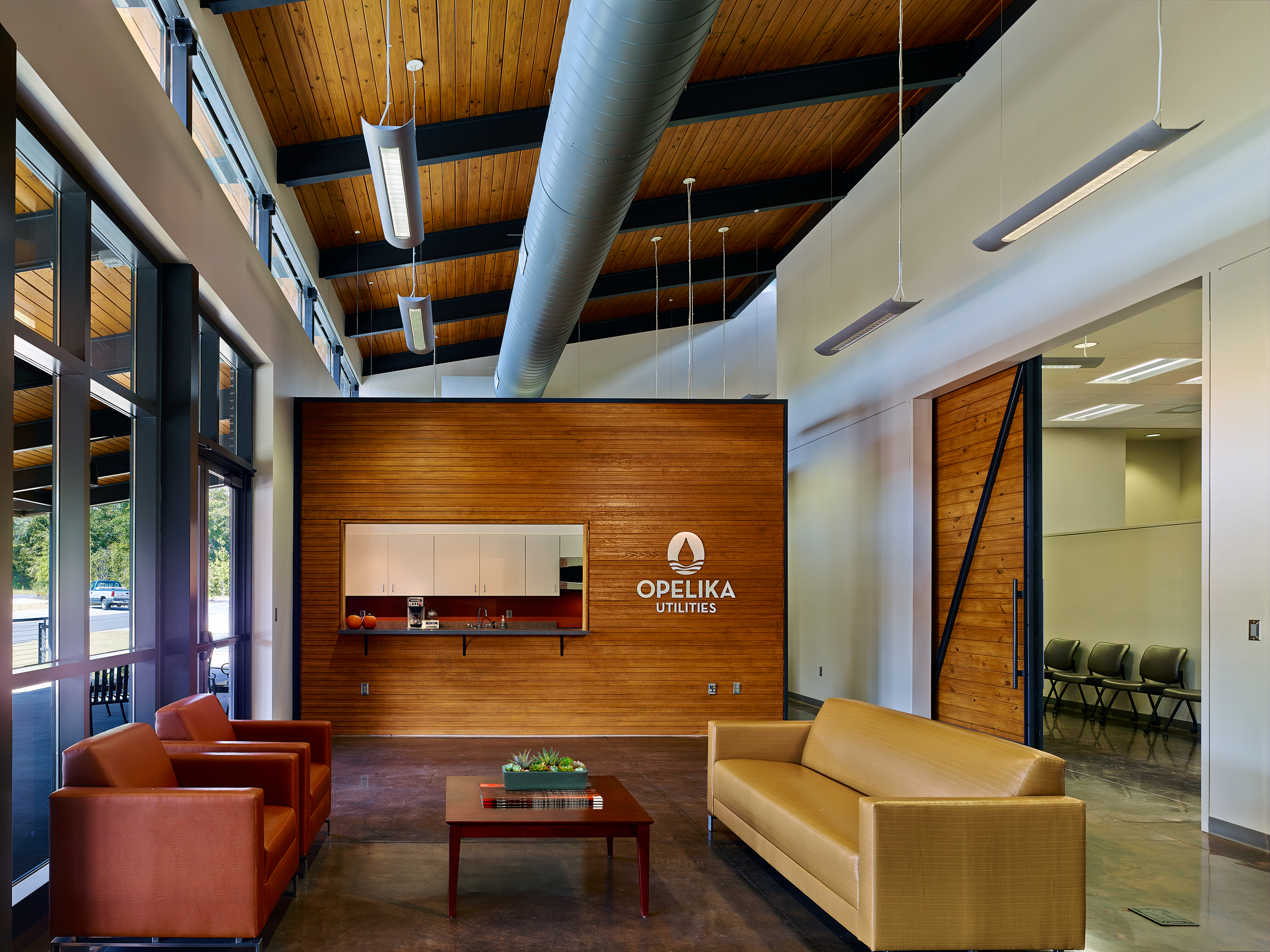 Lobby of Opelika Utilities building with wooden wall reception wall, tall open ceilings as and expansive glass.