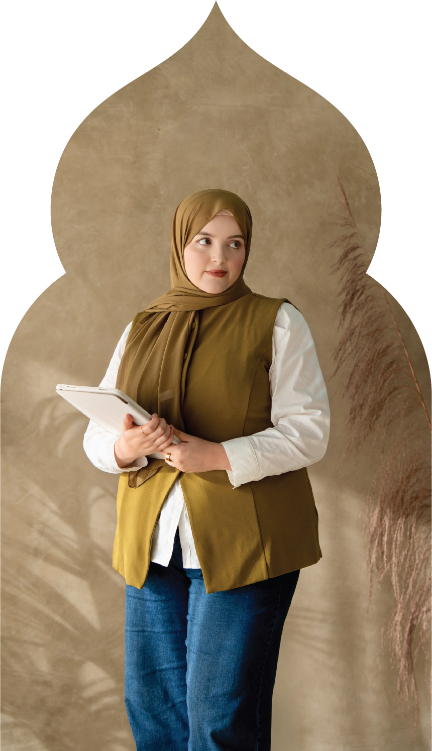 A woman wearing a brown hijab, white shirt, and mustard-colored vest holds a notebook, standing against a beige textured background with dried plant accents.