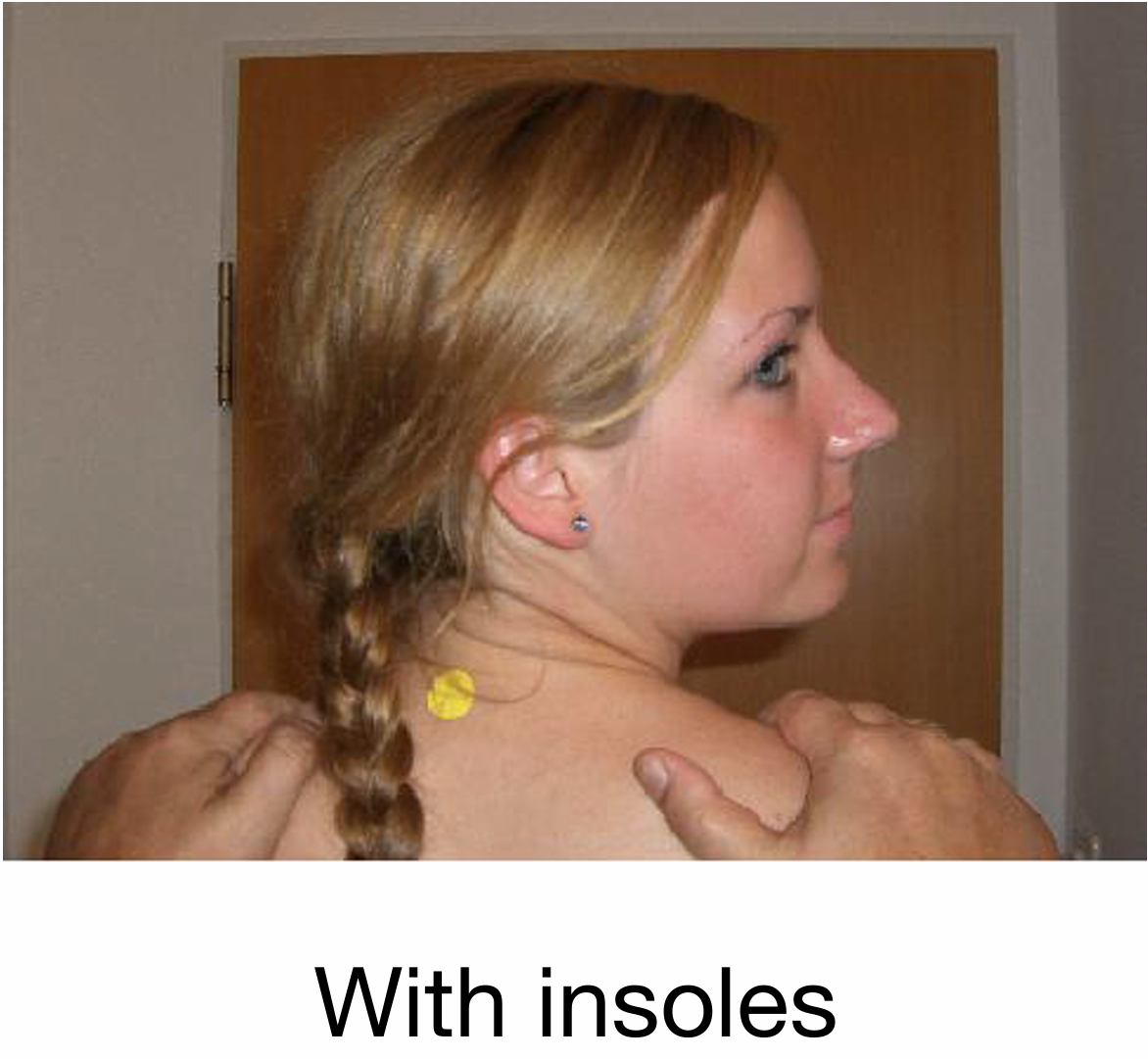 Side profile of a woman with red hair holding her shoulder, with a man's hands on her shoulders. The woman has an earring and a yellow sticker attached to her hair. The background includes a wooden door.