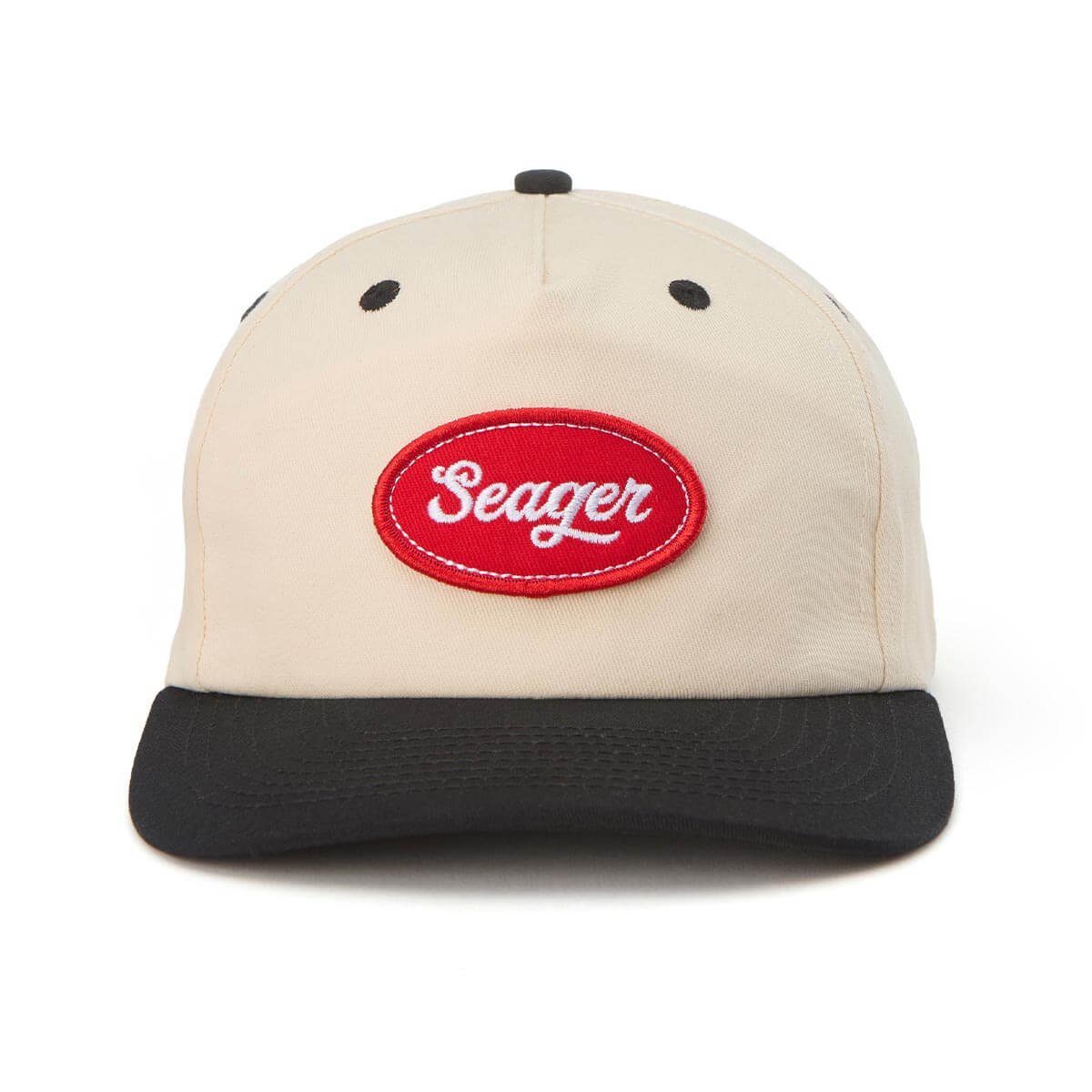 Baseball cap with beige crown, black brim, black eyelets, and red oval patch with white embroidered "Seager" on the front.
