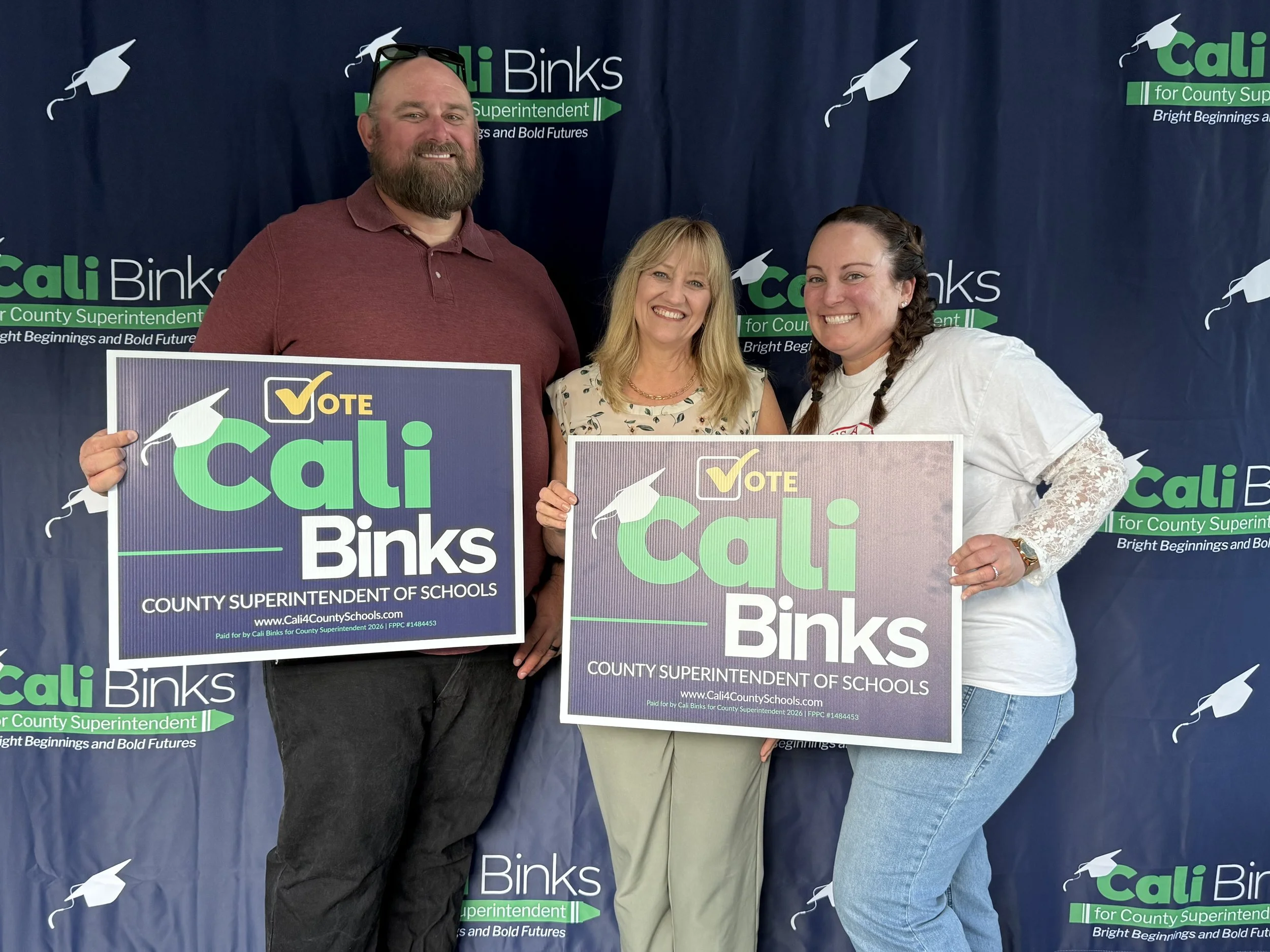 Cali with two community members holding yard signs