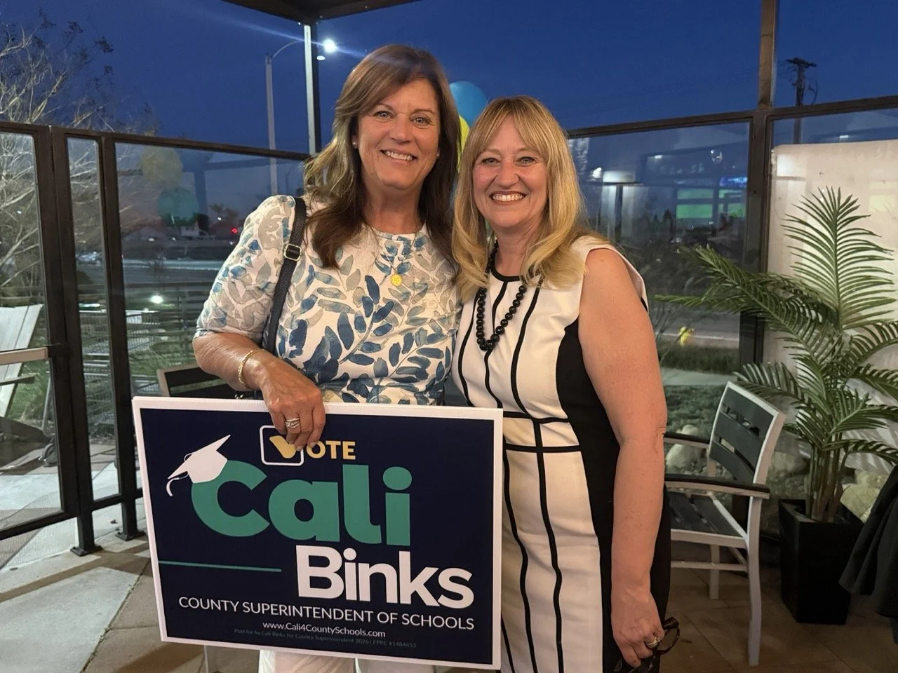 Cali posing with guest with a yard sign.