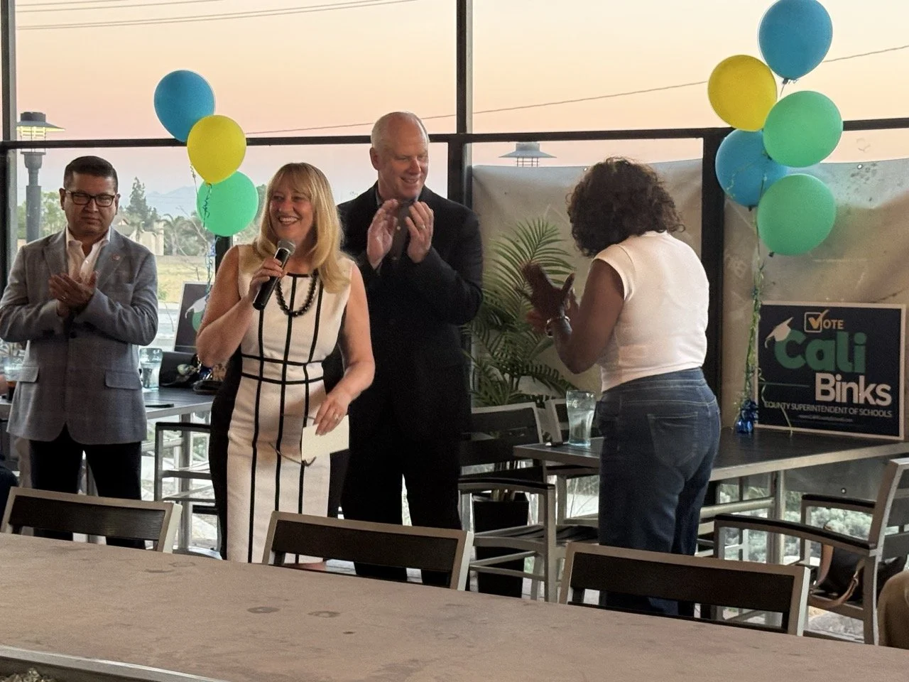 Cali speaking to the crowd while they applaud.