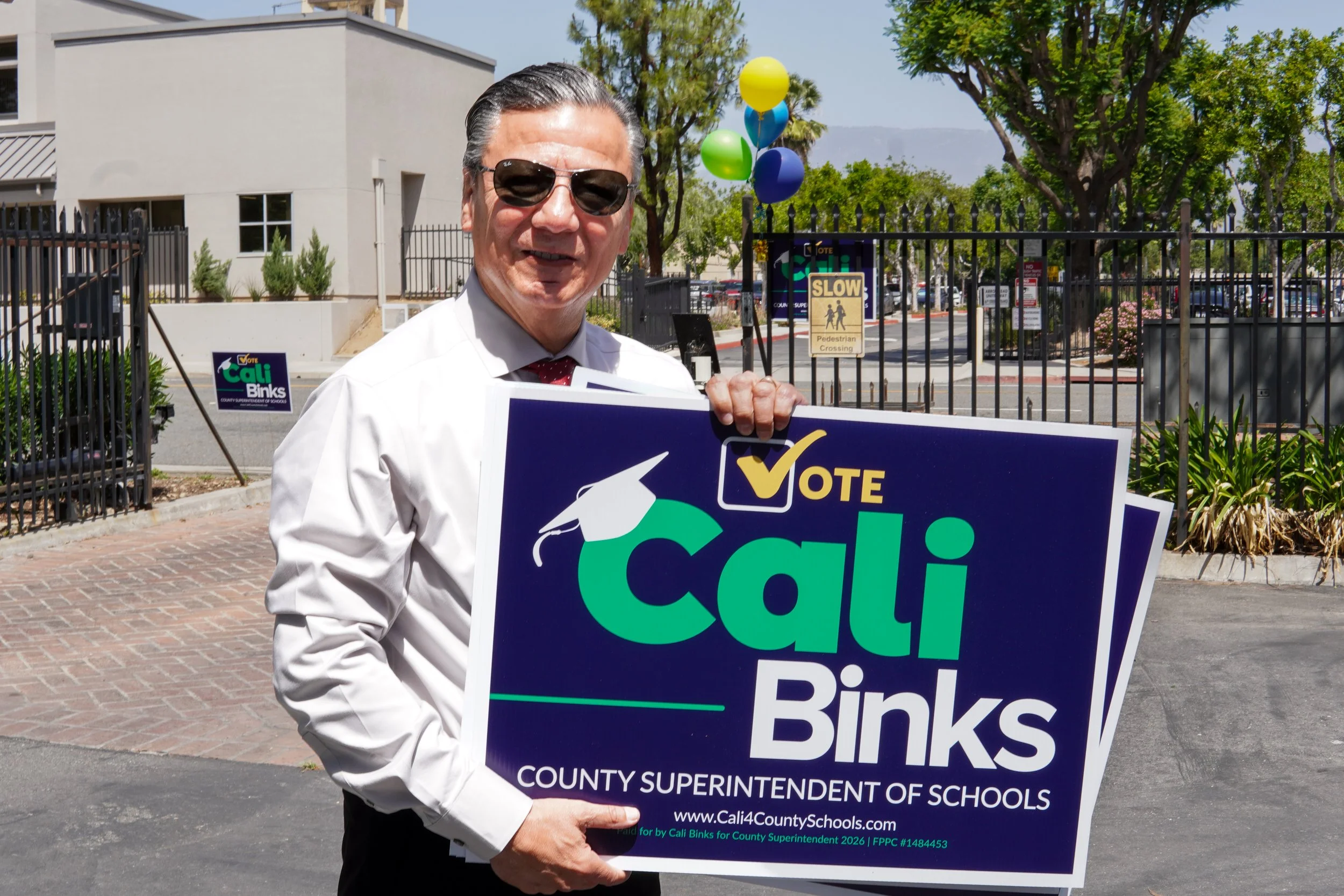 Adult holding a couple of Cali Binks campaign sign