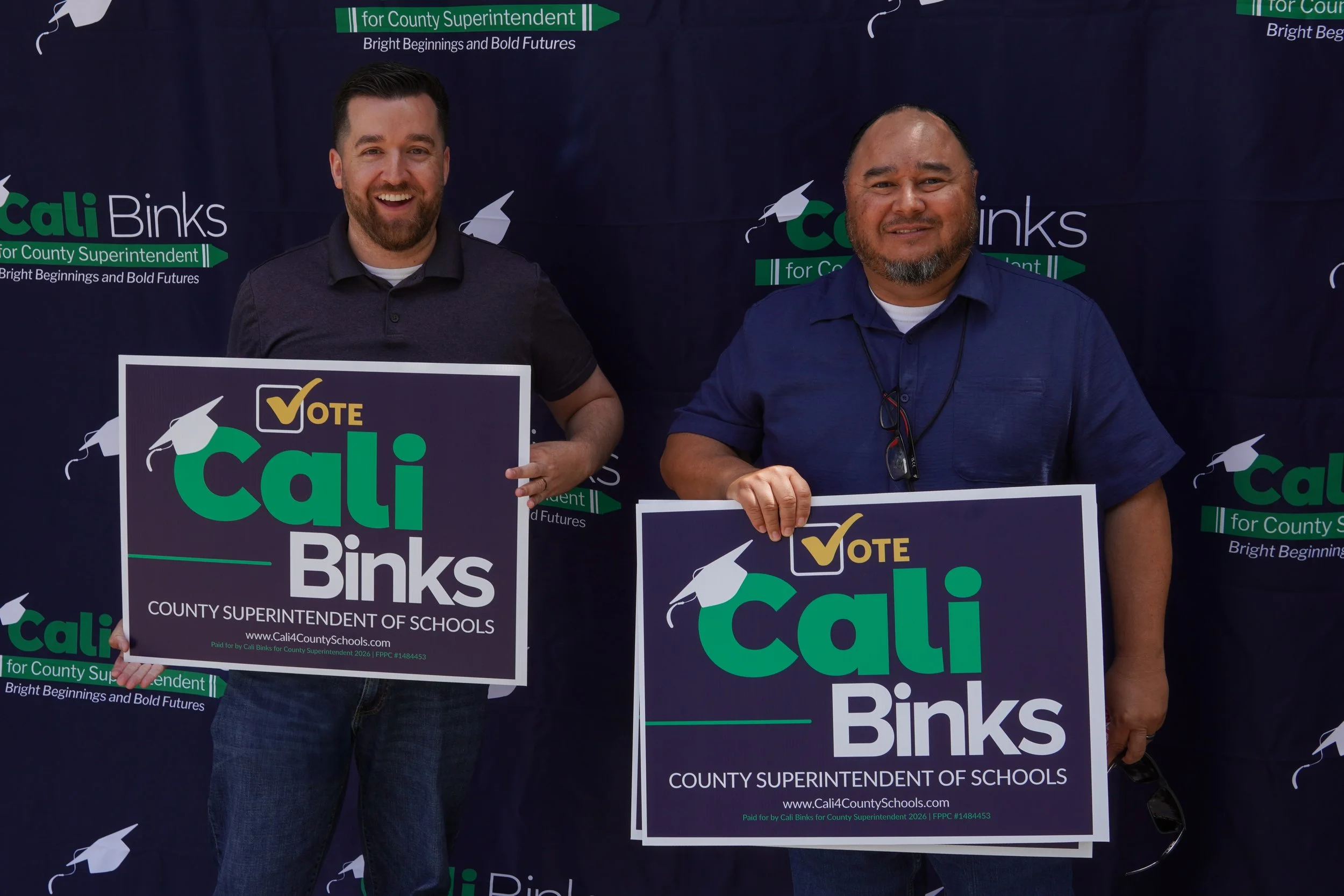 Two adults holding a Cali Binks campaign sign.