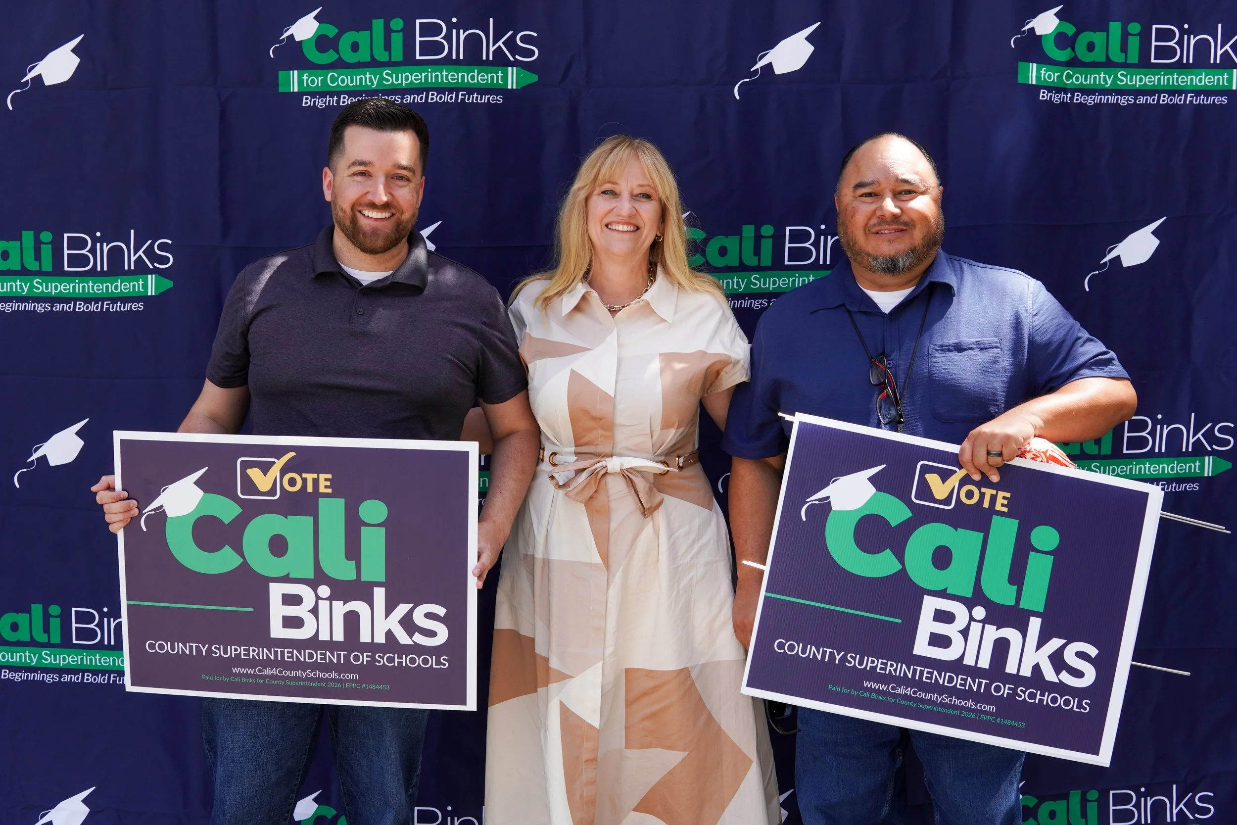 Two adults holding a Cali Binks campaign sign and Cali standing between them.