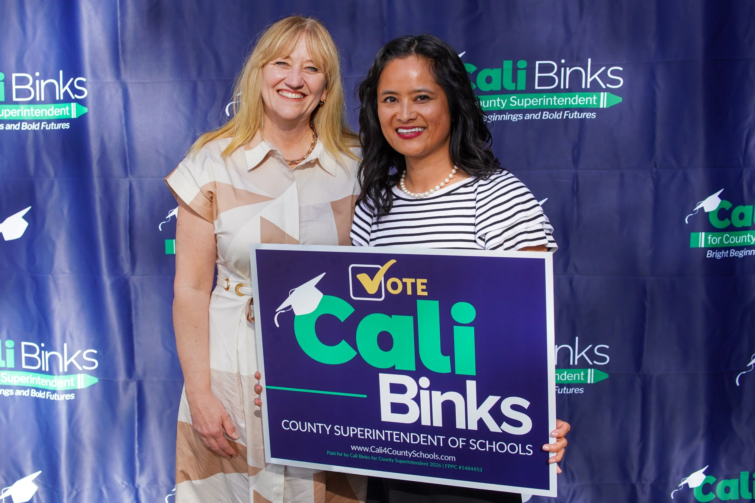 Adult holding a yard sign next to Cali Binks.