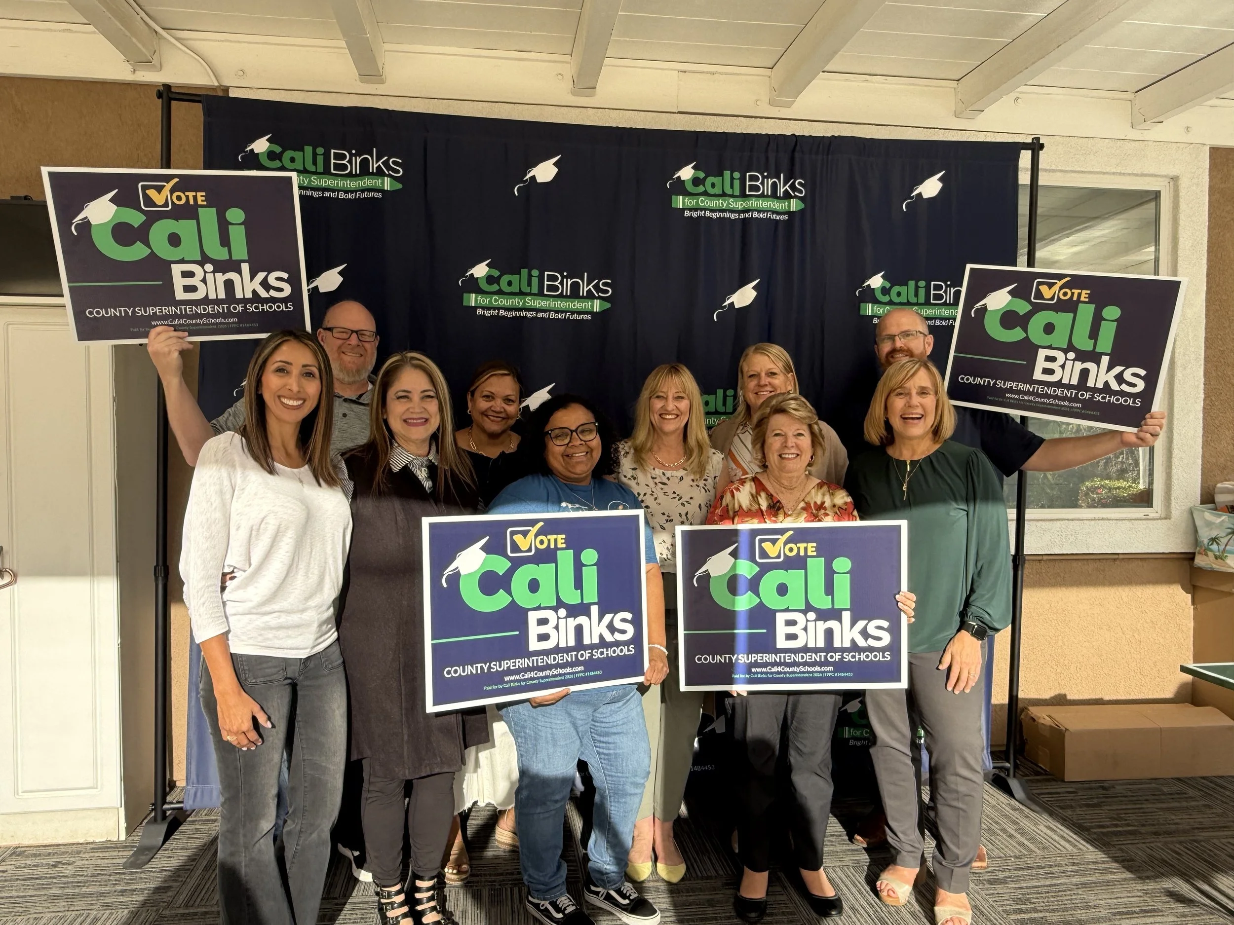 A group of community members holding yard signs with Cali