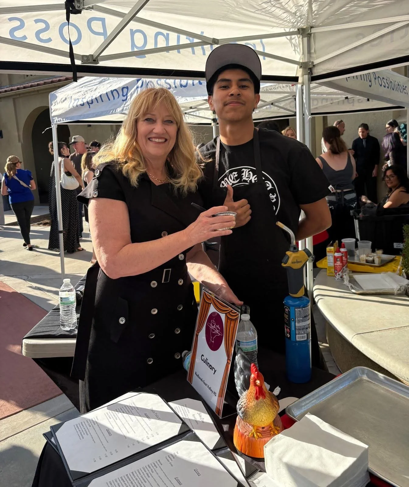 Cali standing next to a high school student wearing an apron and smiling.