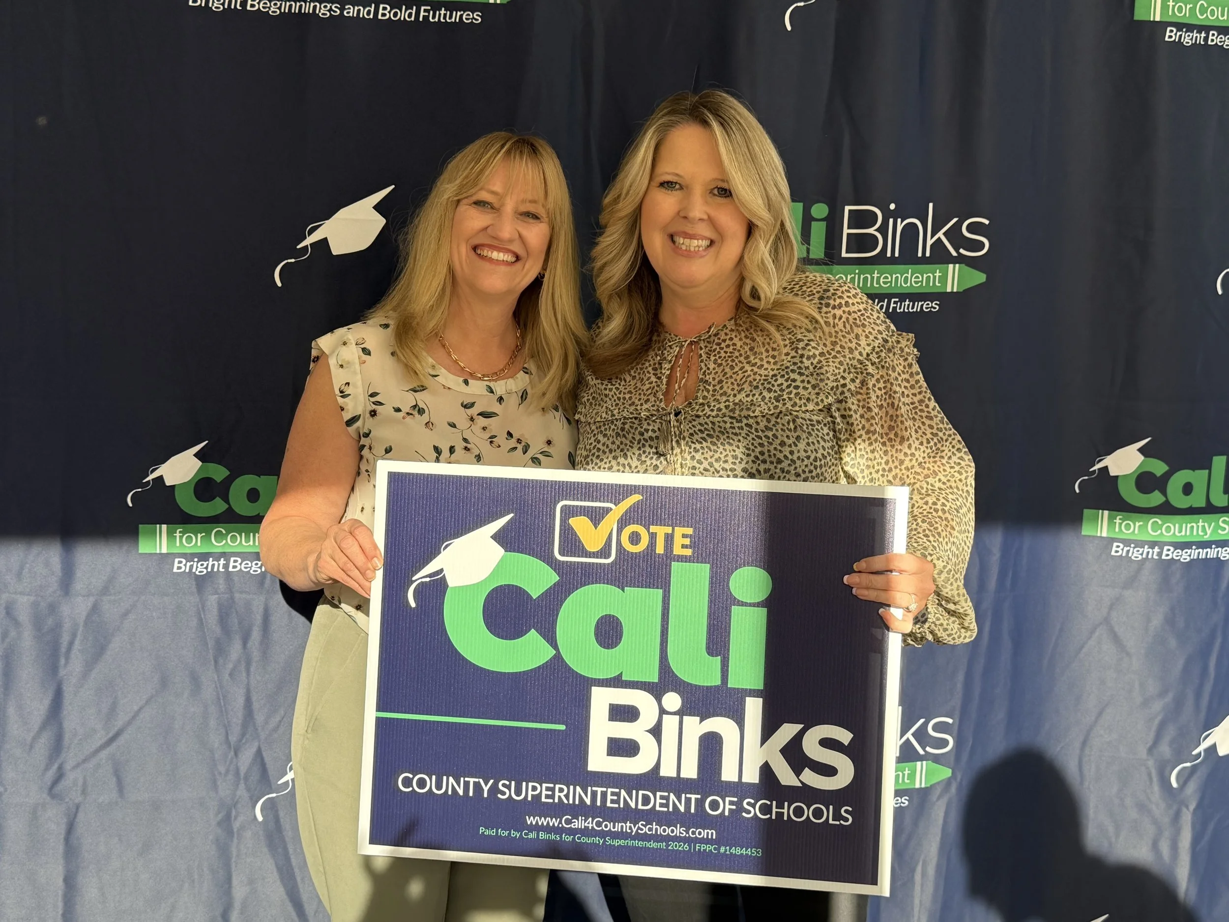 A community member holding a yard sign with Cali