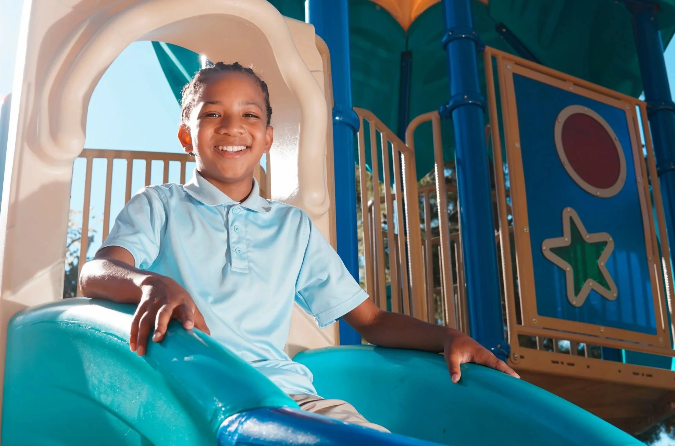 Young student sitting on a playground slide.