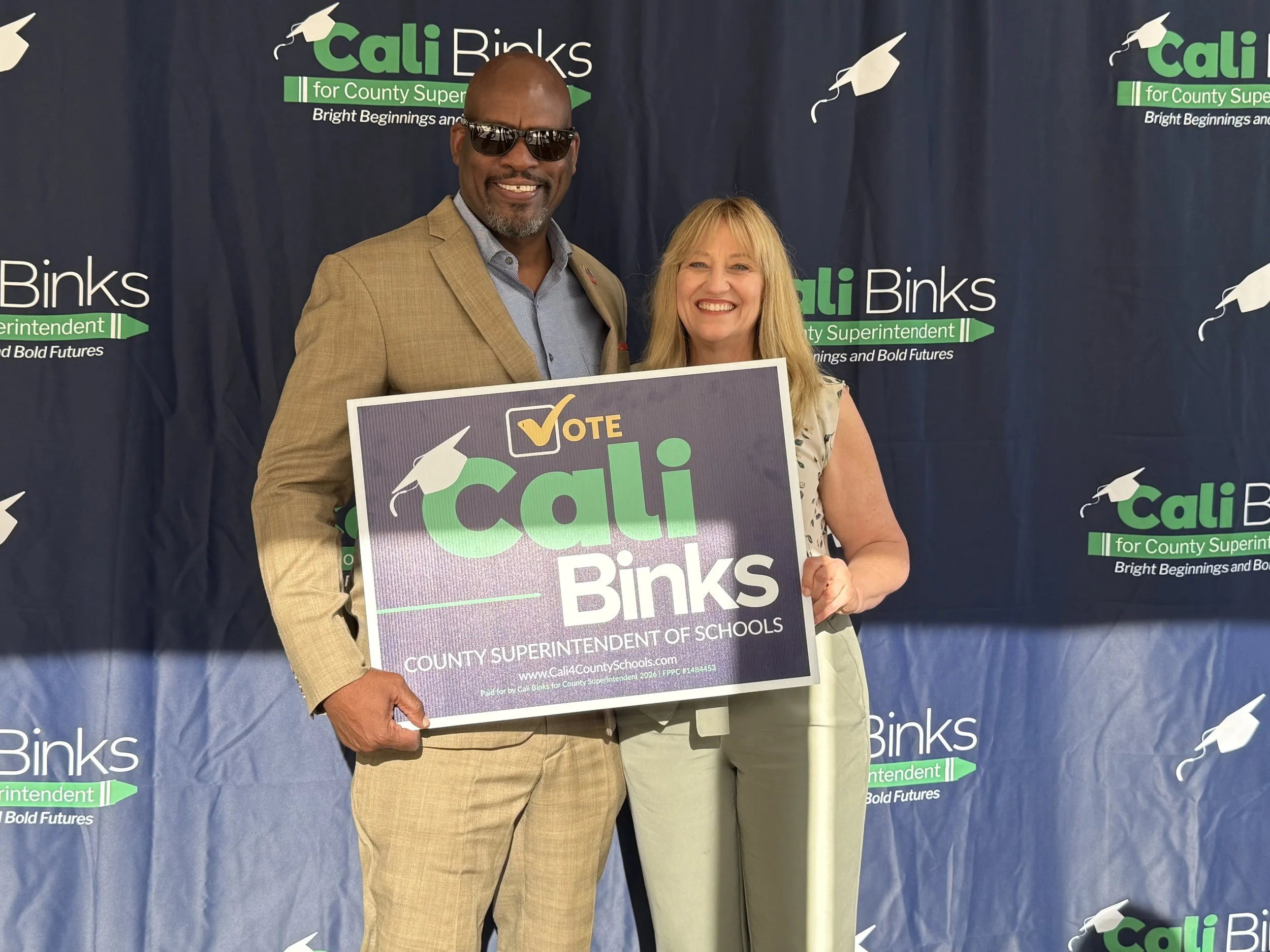 A community member holding a yard sign with Cali