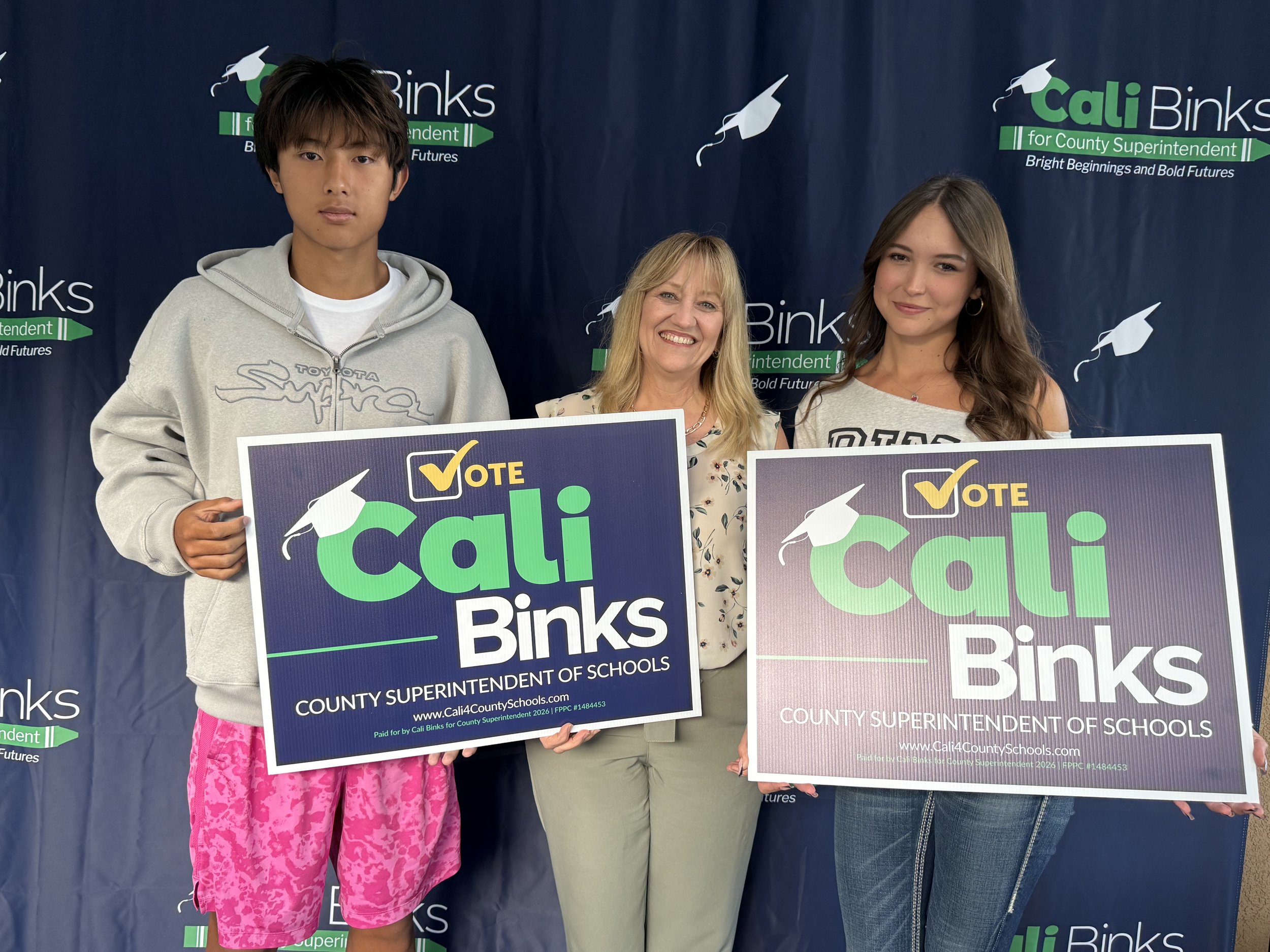 Cali with two high school students holding yard signs